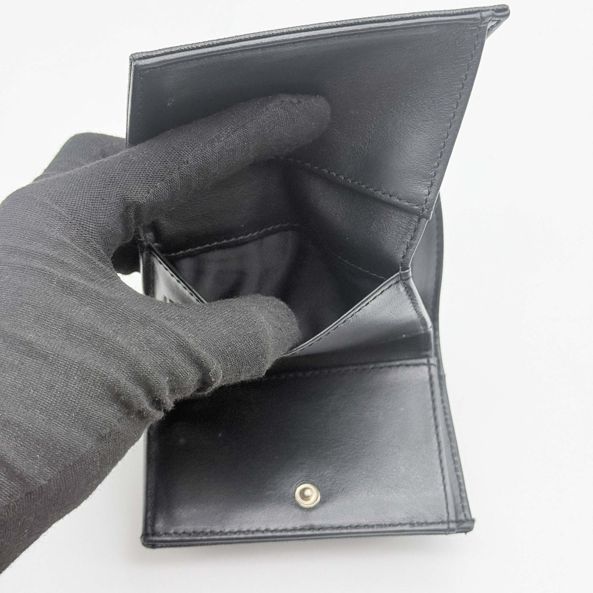 Vivienne Westwood black Saffiano leather trifold wallet with gold Orb detail, photographed closed against a white background.