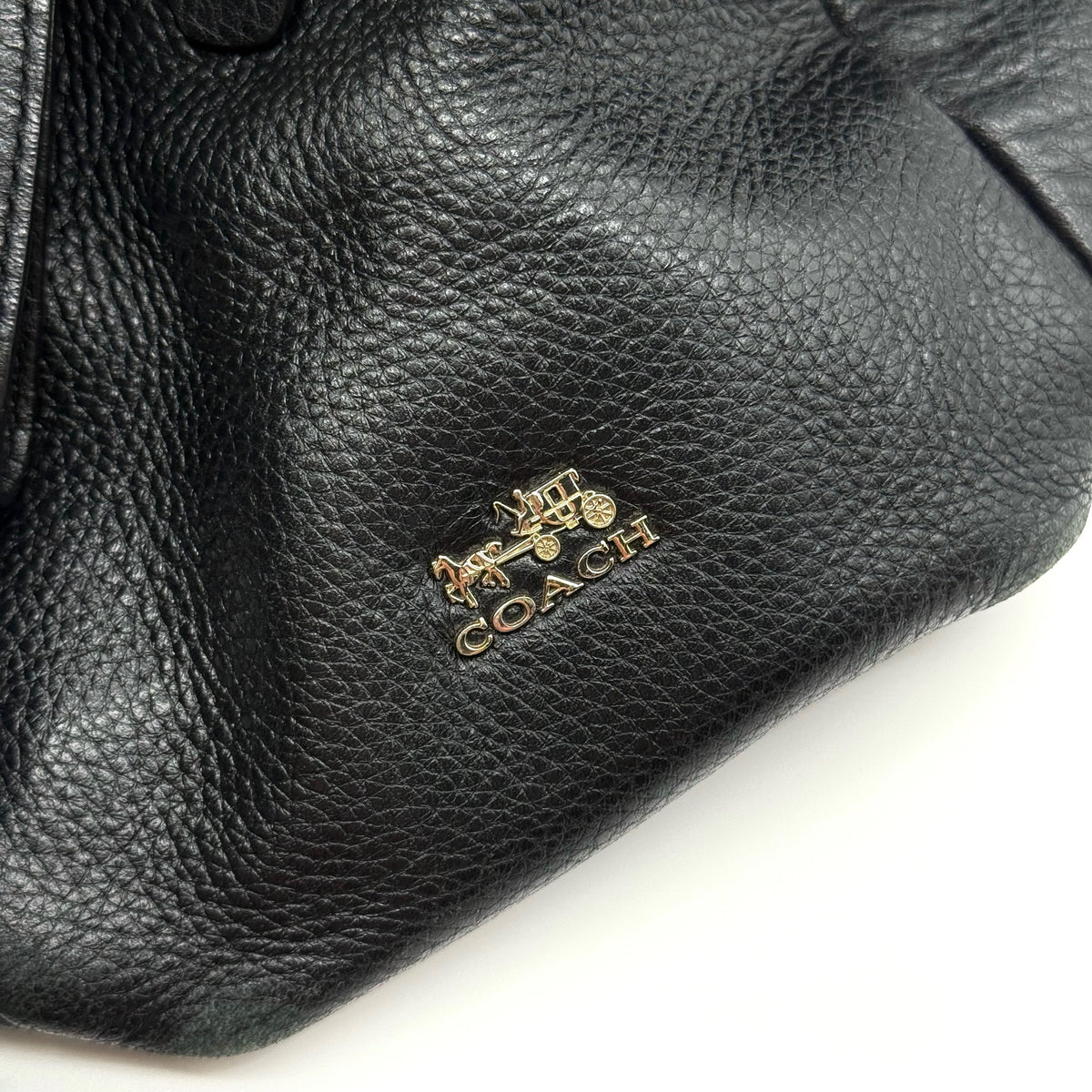 Coach Madison Phoebe Shoulder Bag in black grained leather with gold hardware and dual handles, shown against a white background.