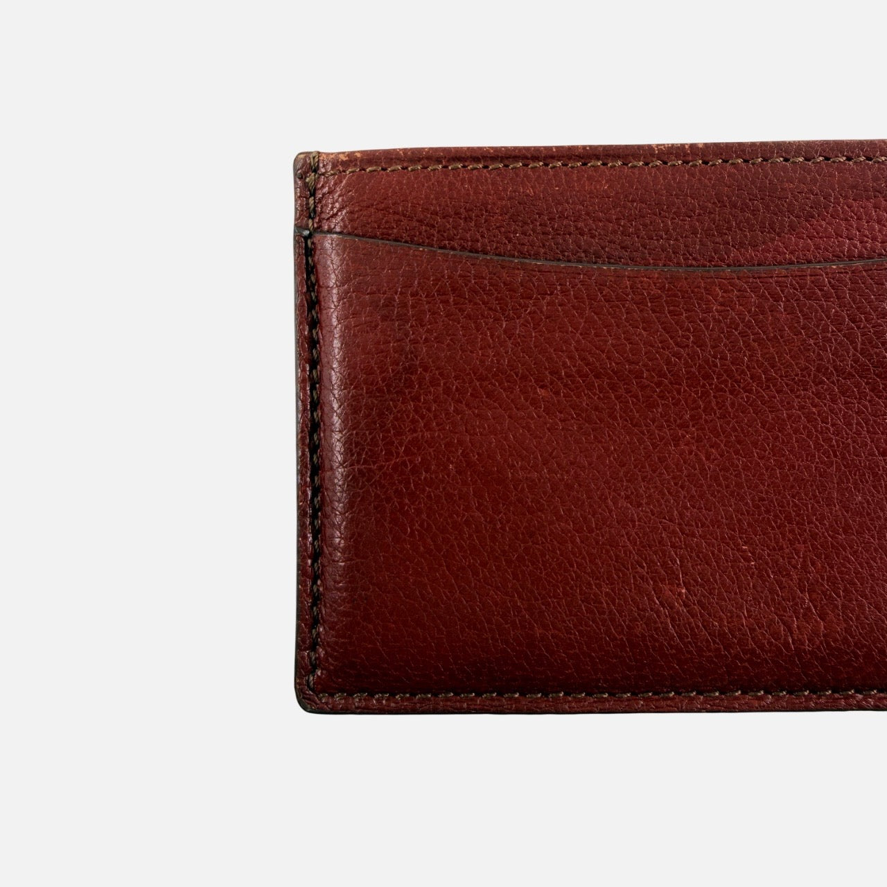 Must de Cartier burgundy leather cardholder with visible natural texture and Cartier script logo, photographed against a clean background.