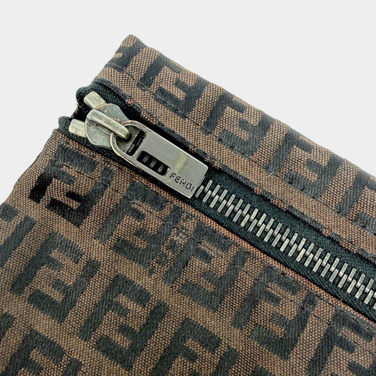 The Fendi FF Zucca Pouch in brown canvas, featuring an all-over FF logo pattern and silver-tone zip closure.
