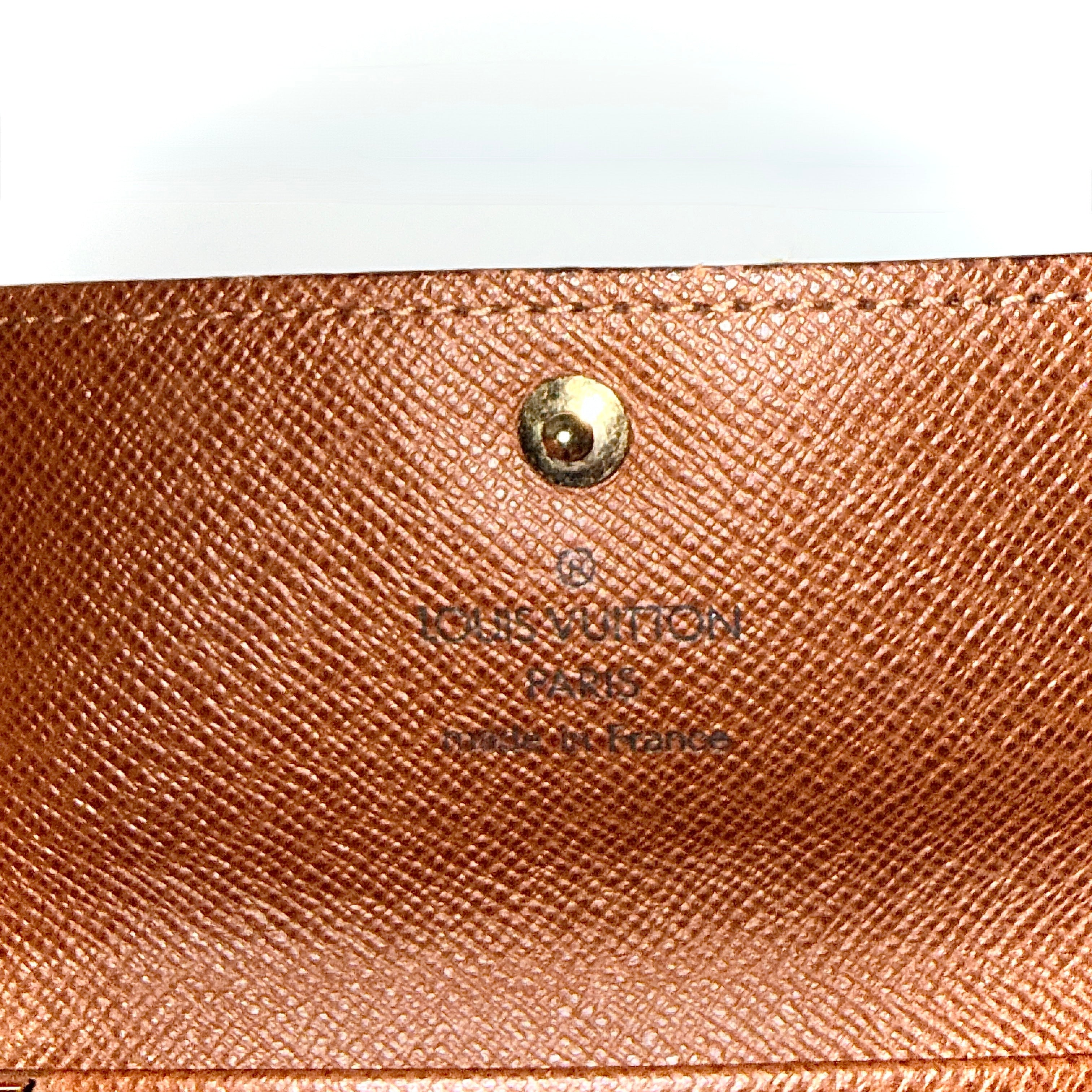 Louis Vuitton monogram key case in brown with gold-tone snap closure and classic LV pattern on coated canvas.