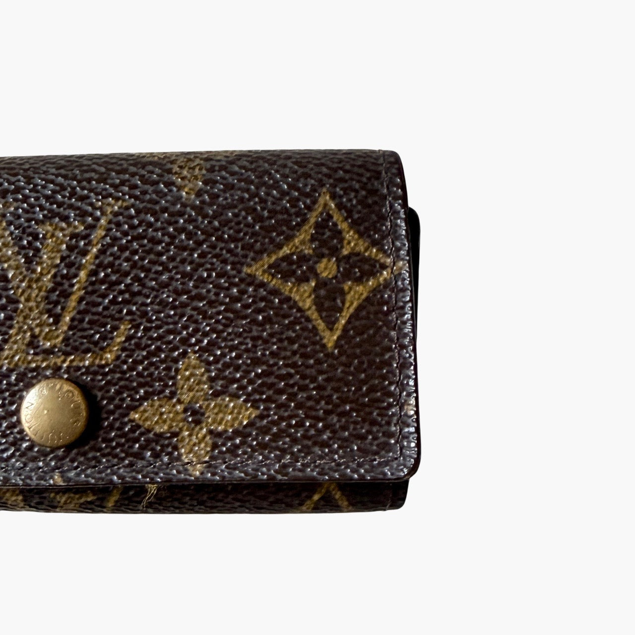 Louis Vuitton monogram key case in brown with gold-tone snap closure and classic LV pattern on coated canvas.