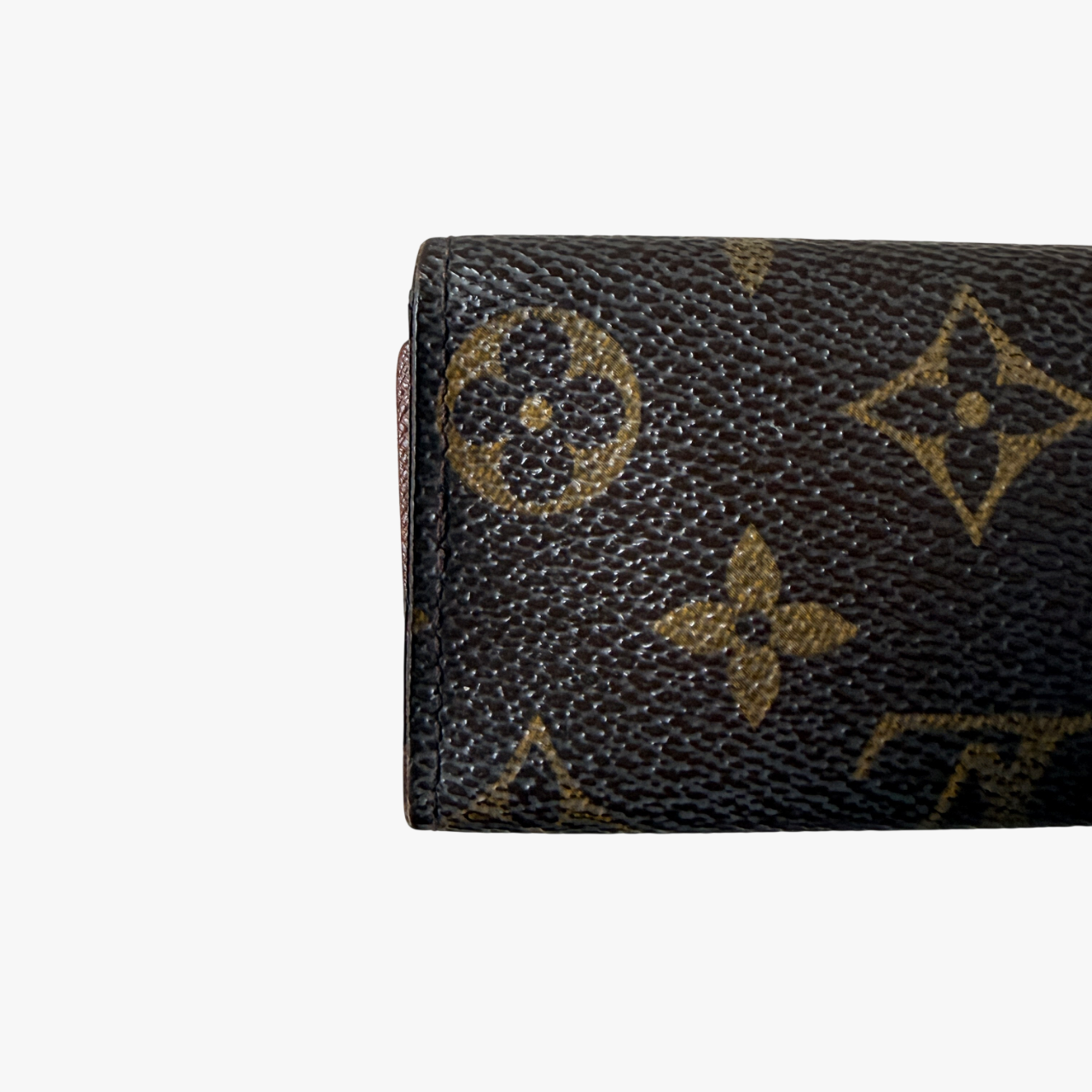 Louis Vuitton monogram key case in brown with gold-tone snap closure and classic LV pattern on coated canvas.