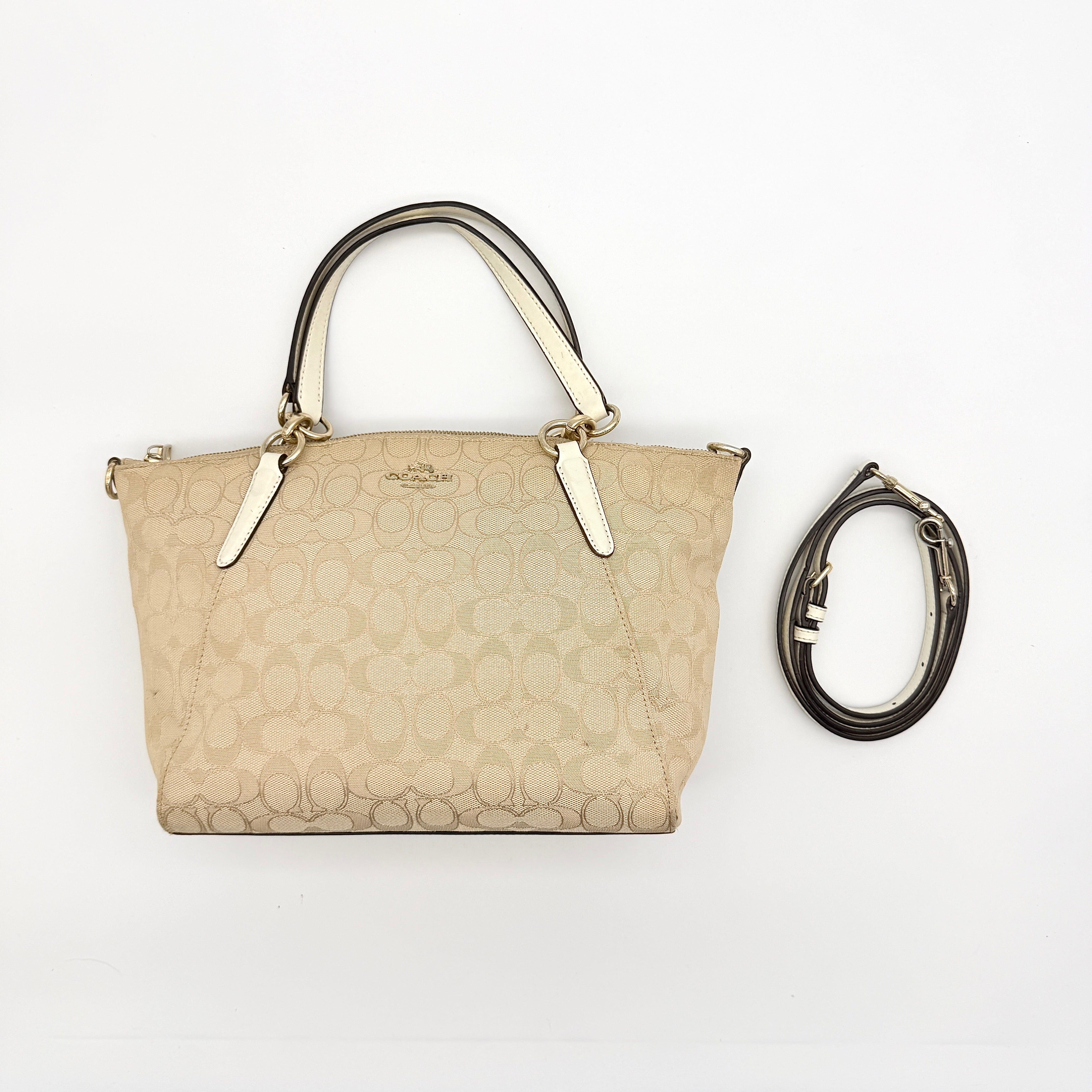 Coach Kelsey 2Way shoulder bag in beige signature canvas with cream leather handles and detachable strap, shown on a white background.