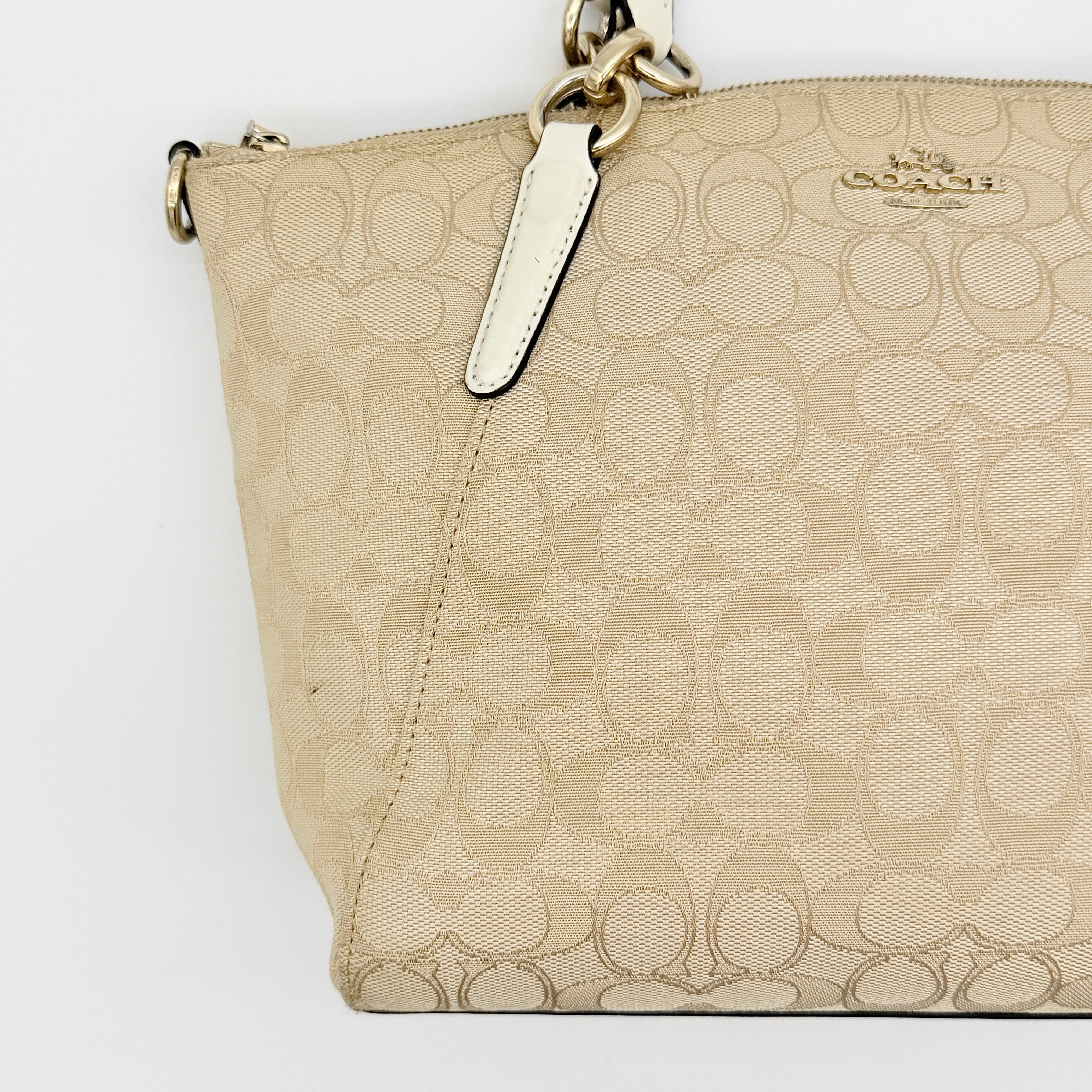 Coach Kelsey 2Way shoulder bag in beige signature canvas with cream leather handles and detachable strap, shown on a white background.
