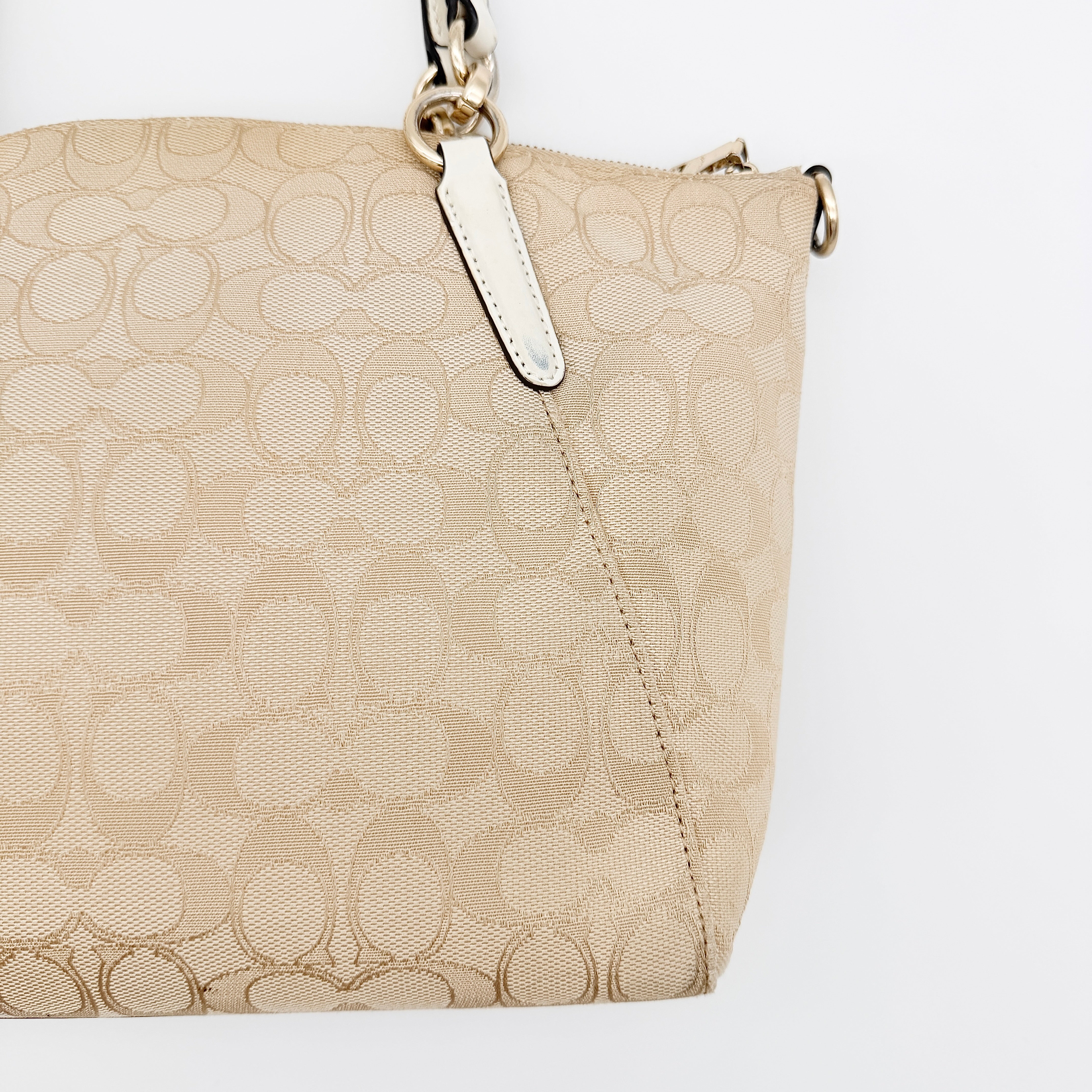 Coach Kelsey 2Way shoulder bag in beige signature canvas with cream leather handles and detachable strap, shown on a white background.