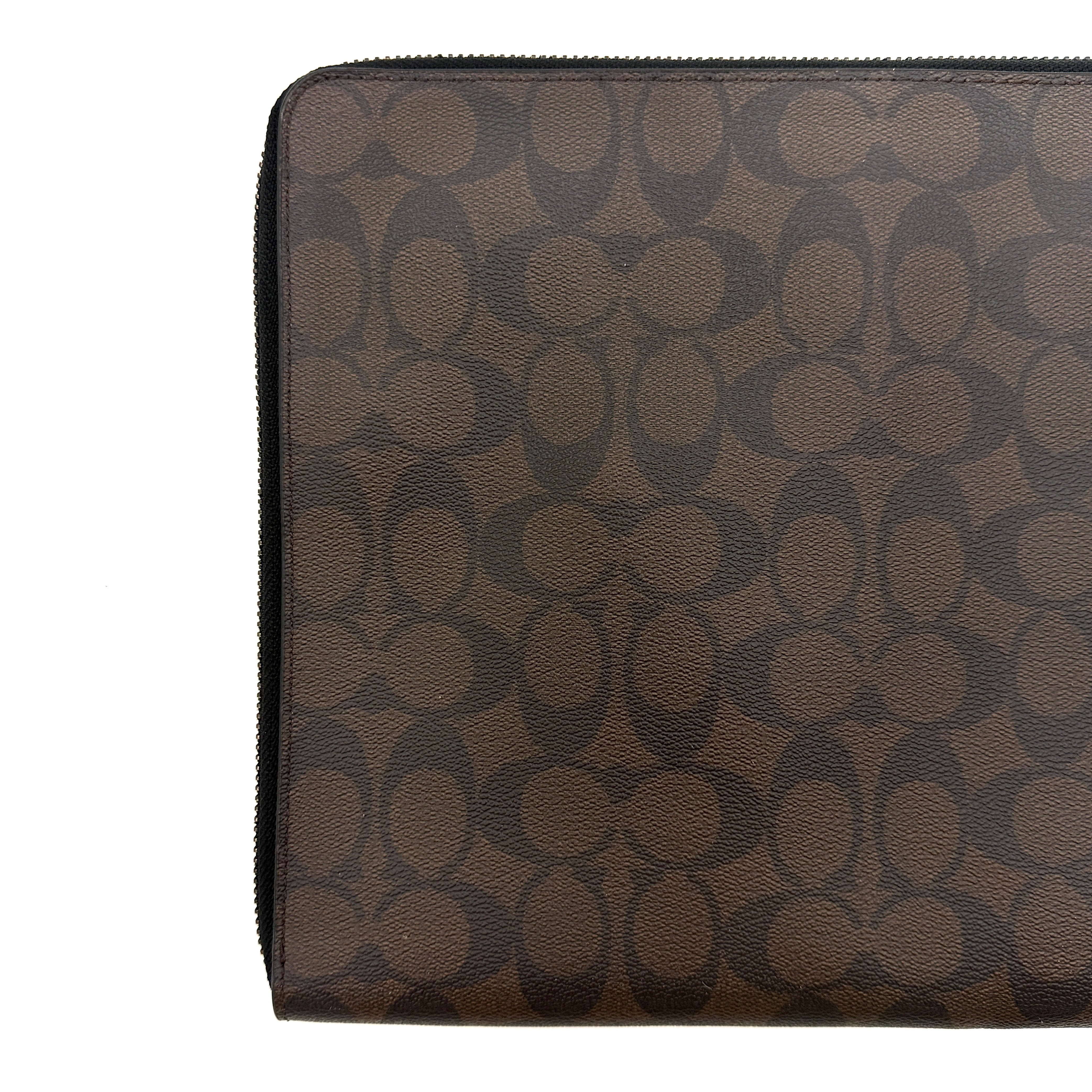 Coach Signature Zip Portfolio in brown and black monogram canvas with zip-around closure, displayed flat against a white background.