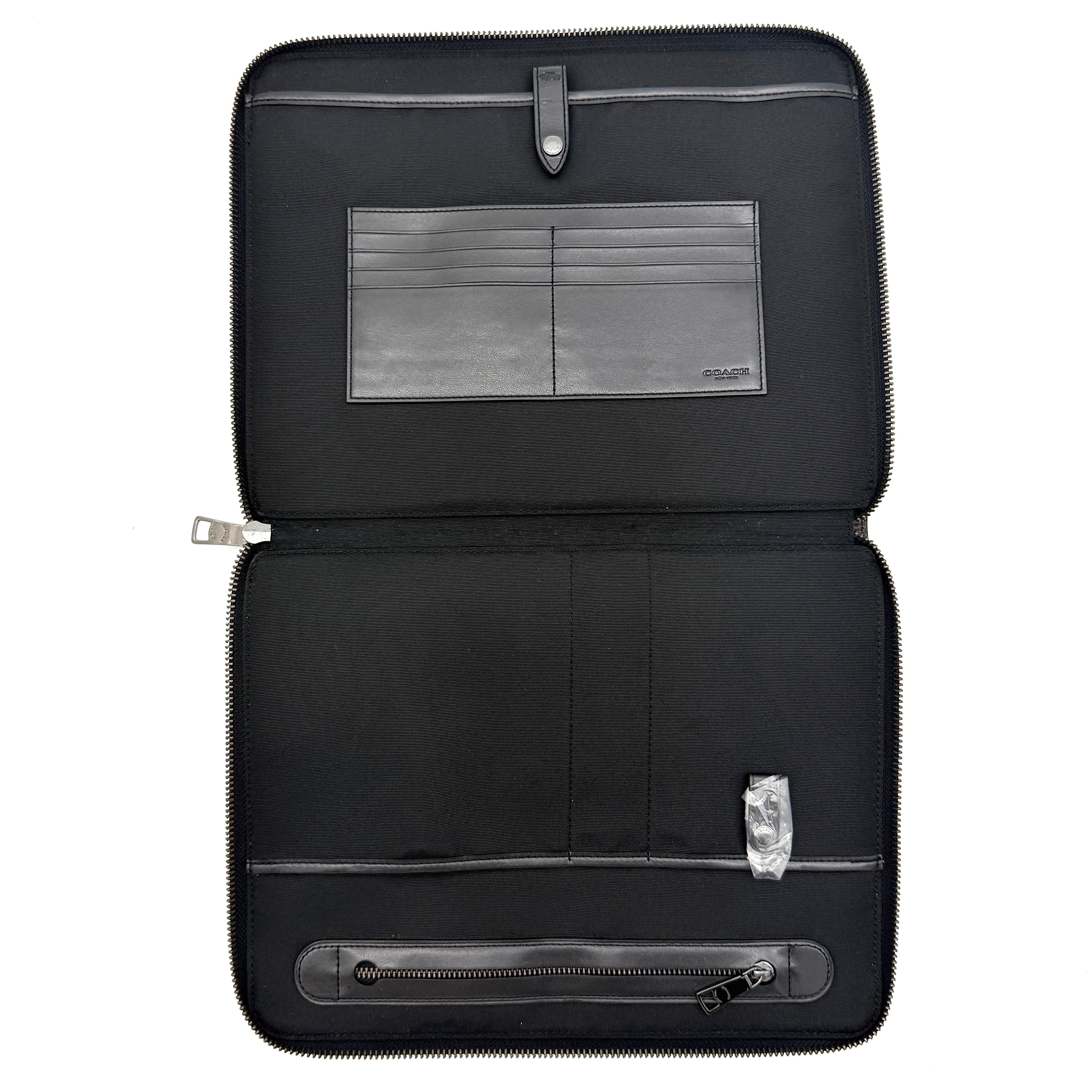 Coach Signature Zip Portfolio in brown and black monogram canvas with zip-around closure, displayed flat against a white background.