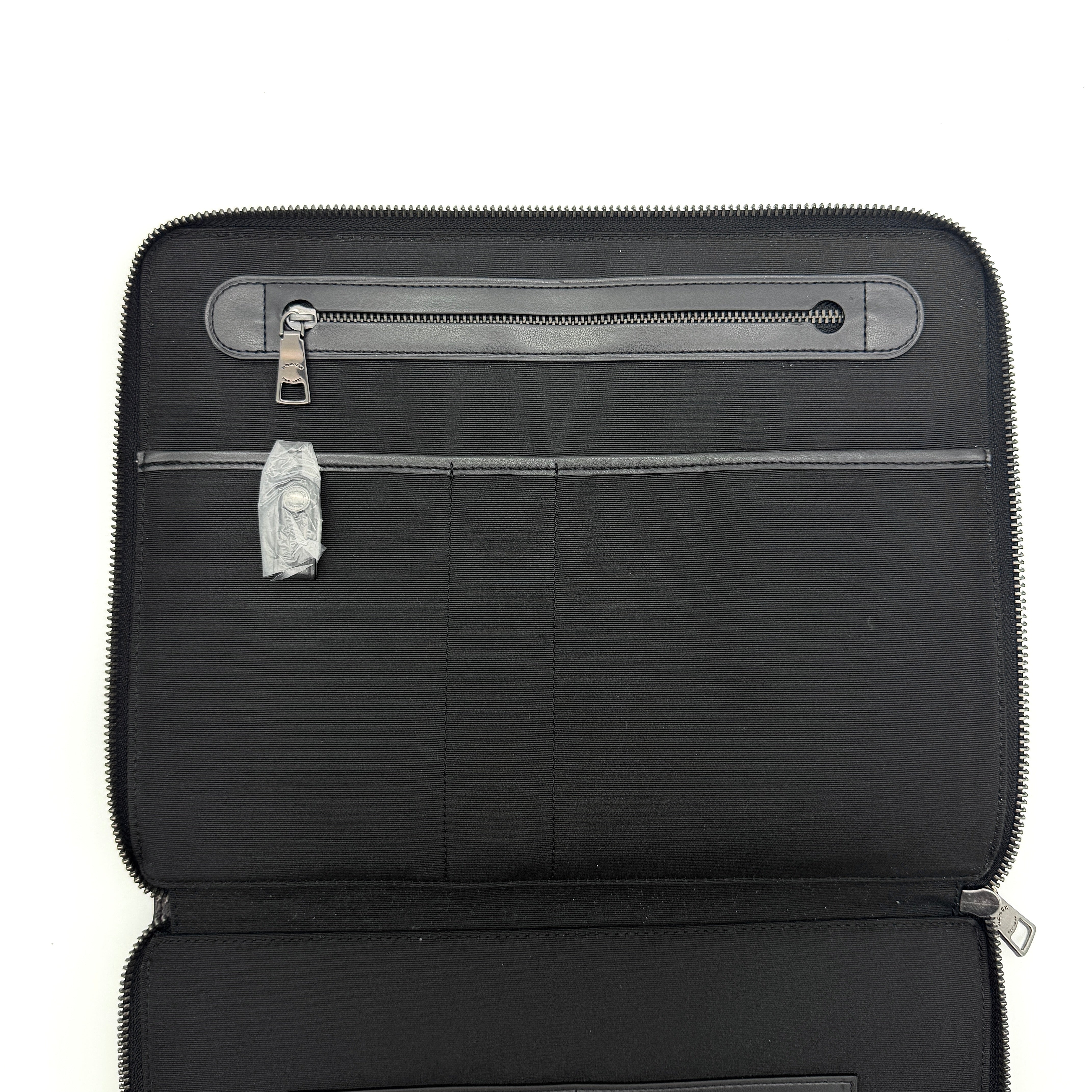Coach Signature Zip Portfolio in brown and black monogram canvas with zip-around closure, displayed flat against a white background.