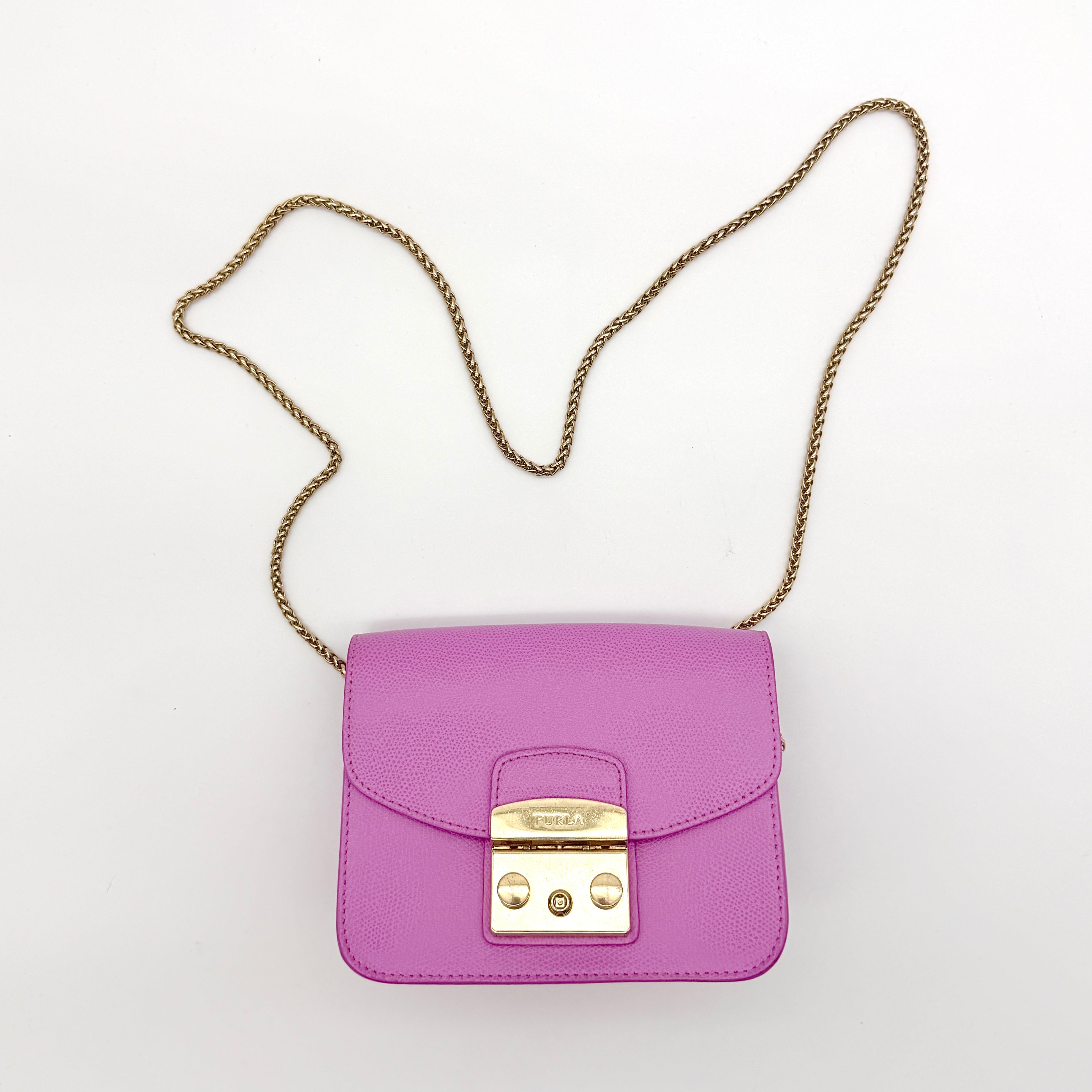 Furla Metropolis crossbody bag in pink grained leather with gold hardware and chain strap, displayed against a white background.