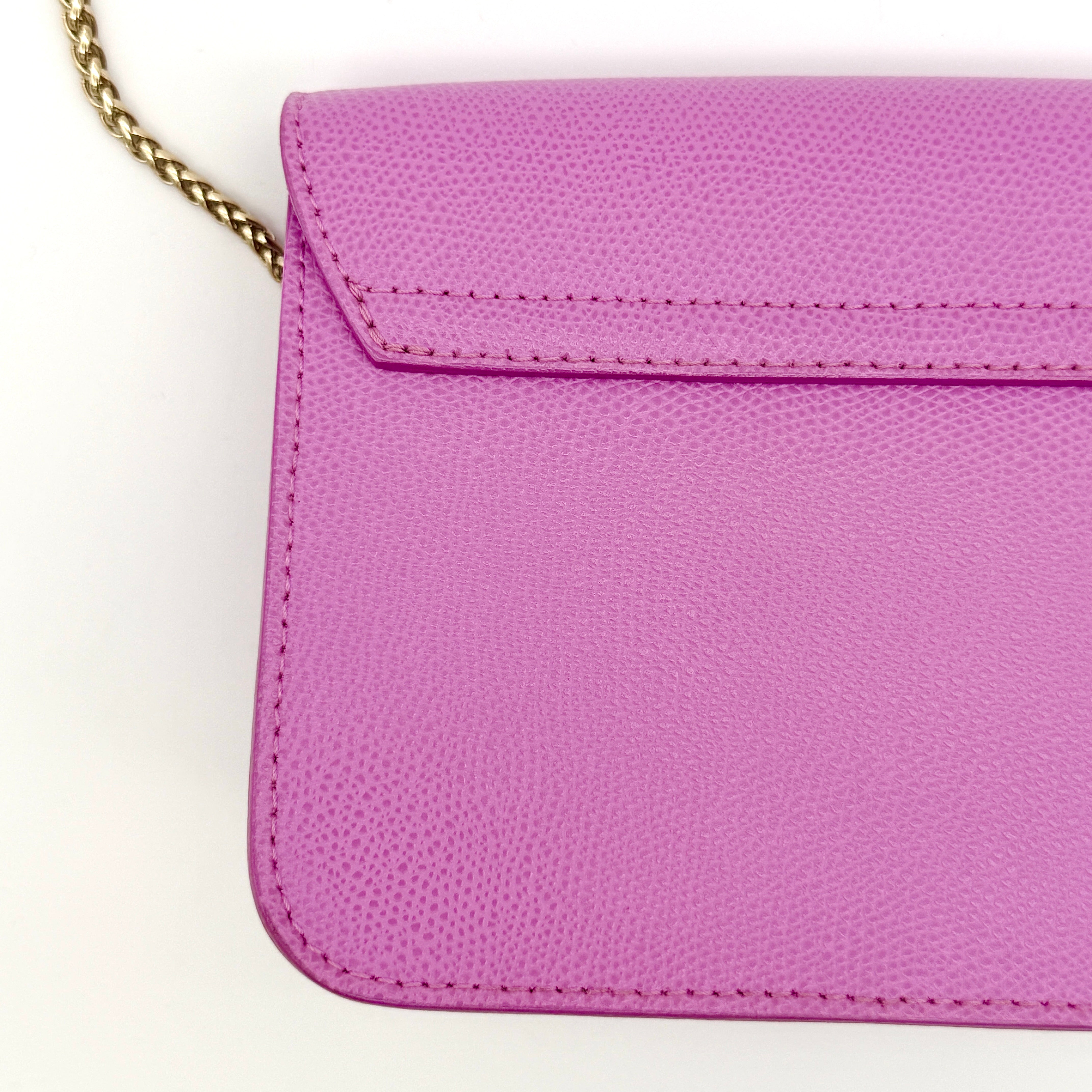 Furla Metropolis crossbody bag in pink grained leather with gold hardware and chain strap, displayed against a white background.