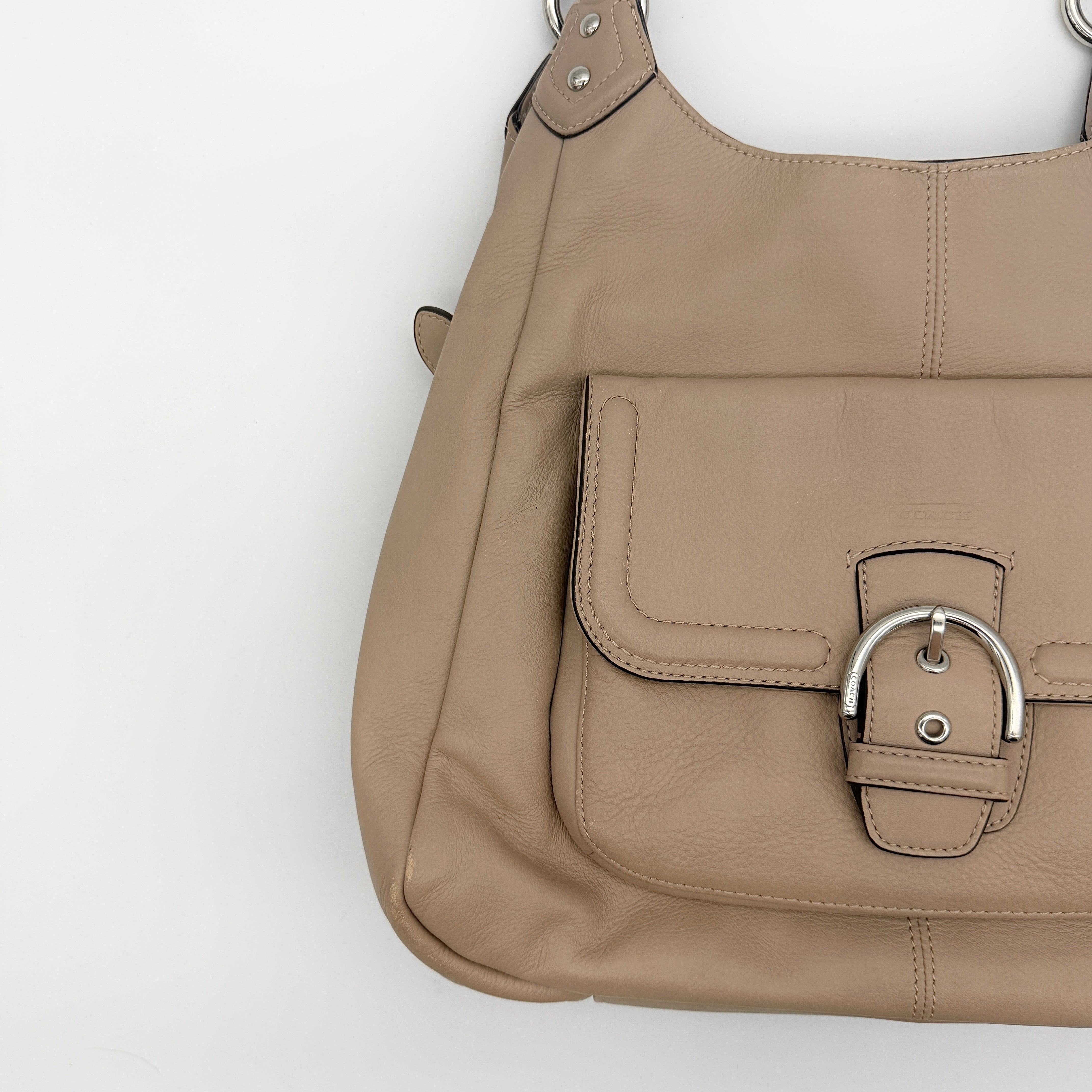 Coach Campbell Hobo shoulder bag in beige leather with silver hardware and front pocket, shown against a white background.