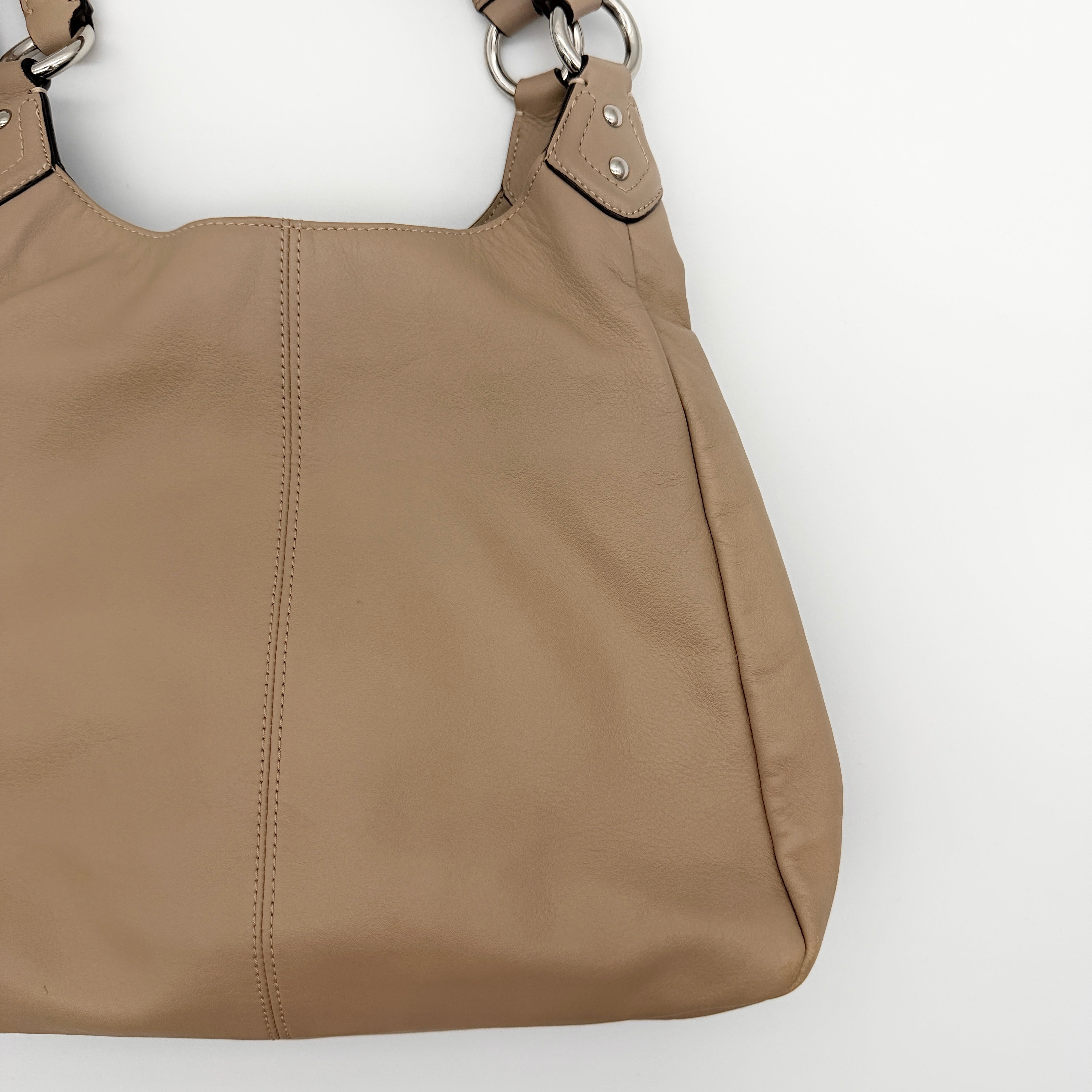 Coach Campbell Hobo shoulder bag in beige leather with silver hardware and front pocket, shown against a white background.