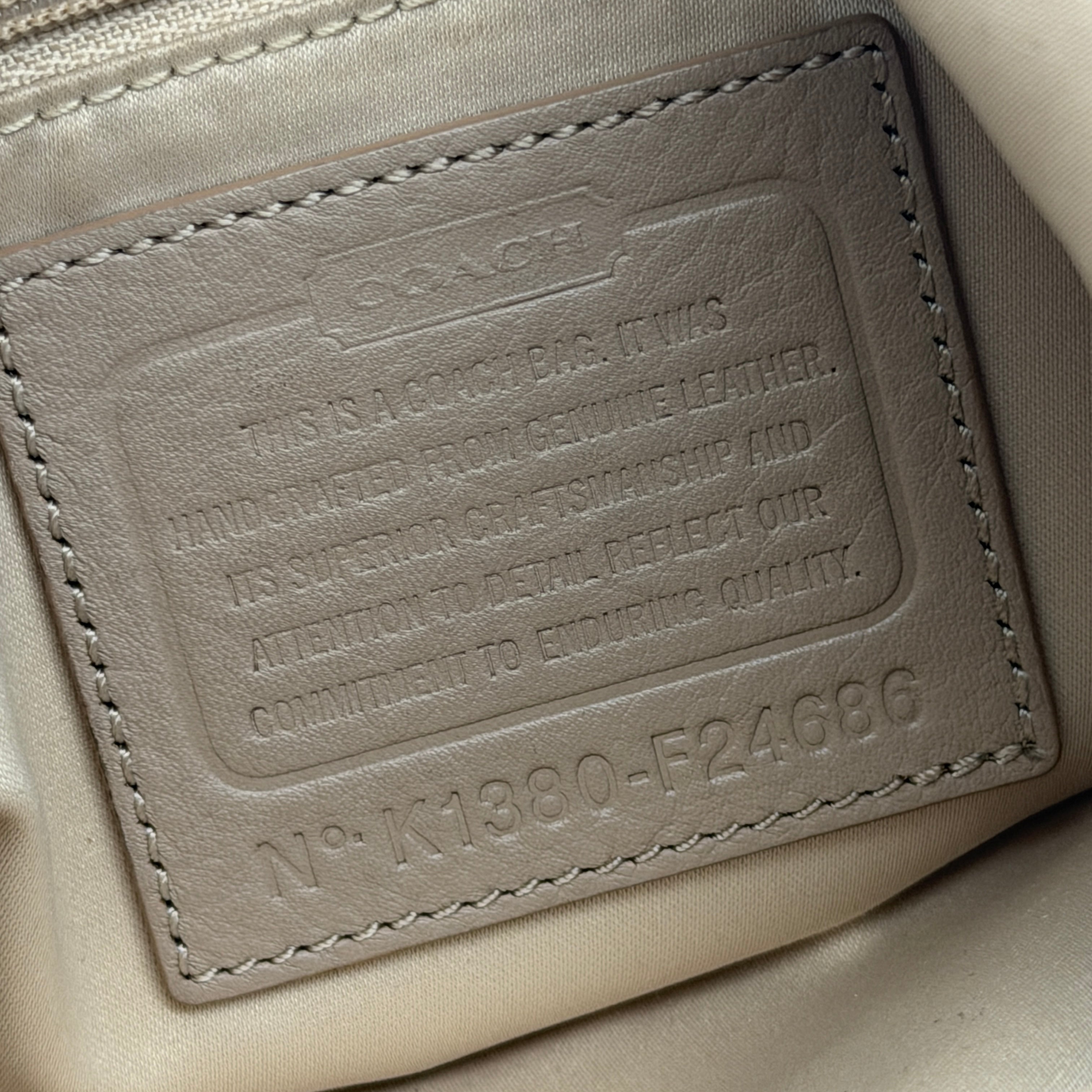 Coach Campbell Hobo shoulder bag in beige leather with silver hardware and front pocket, shown against a white background.