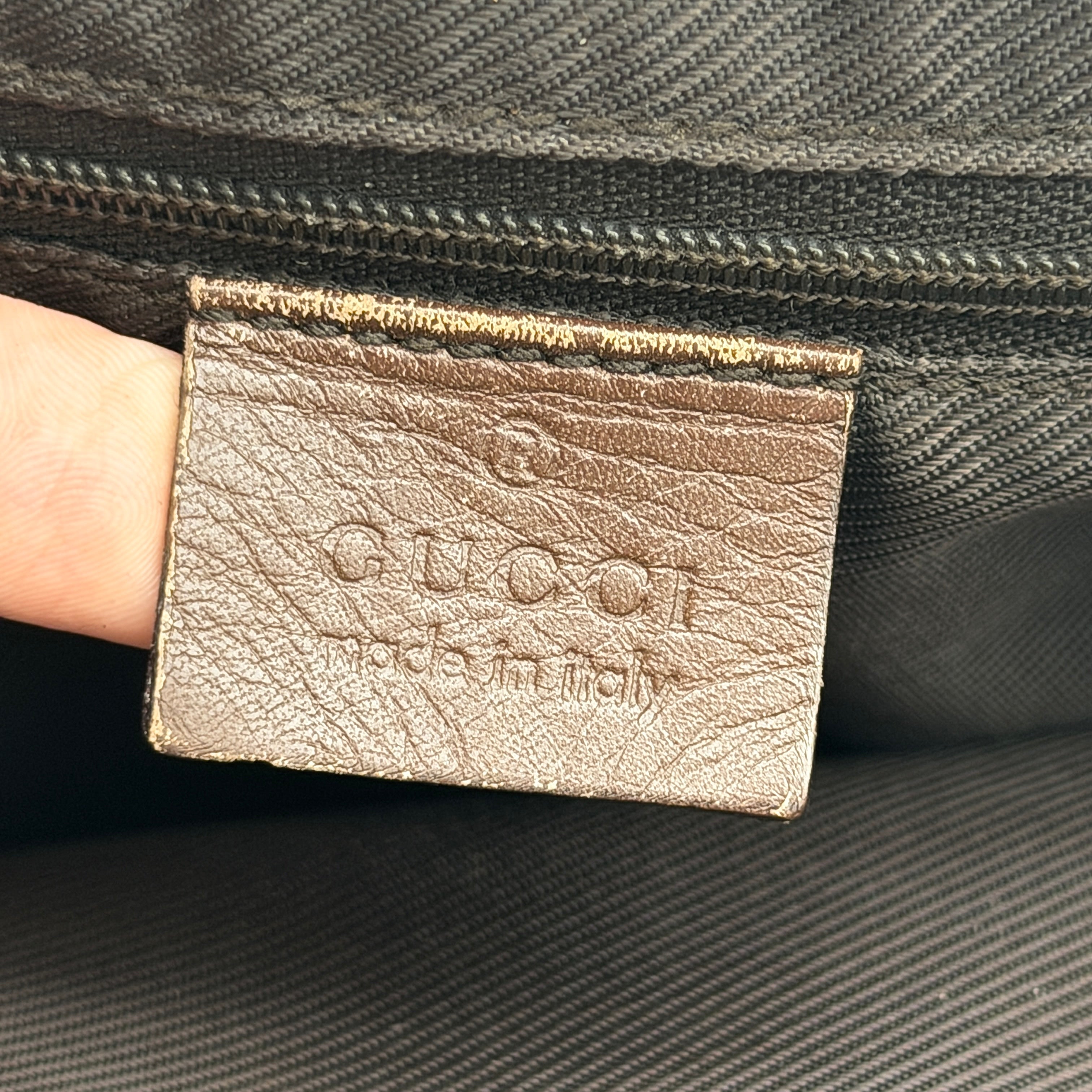 Front view of a Gucci GG Monogram Tote Bag in beige and brown canvas with dark leather trim and structured handles.