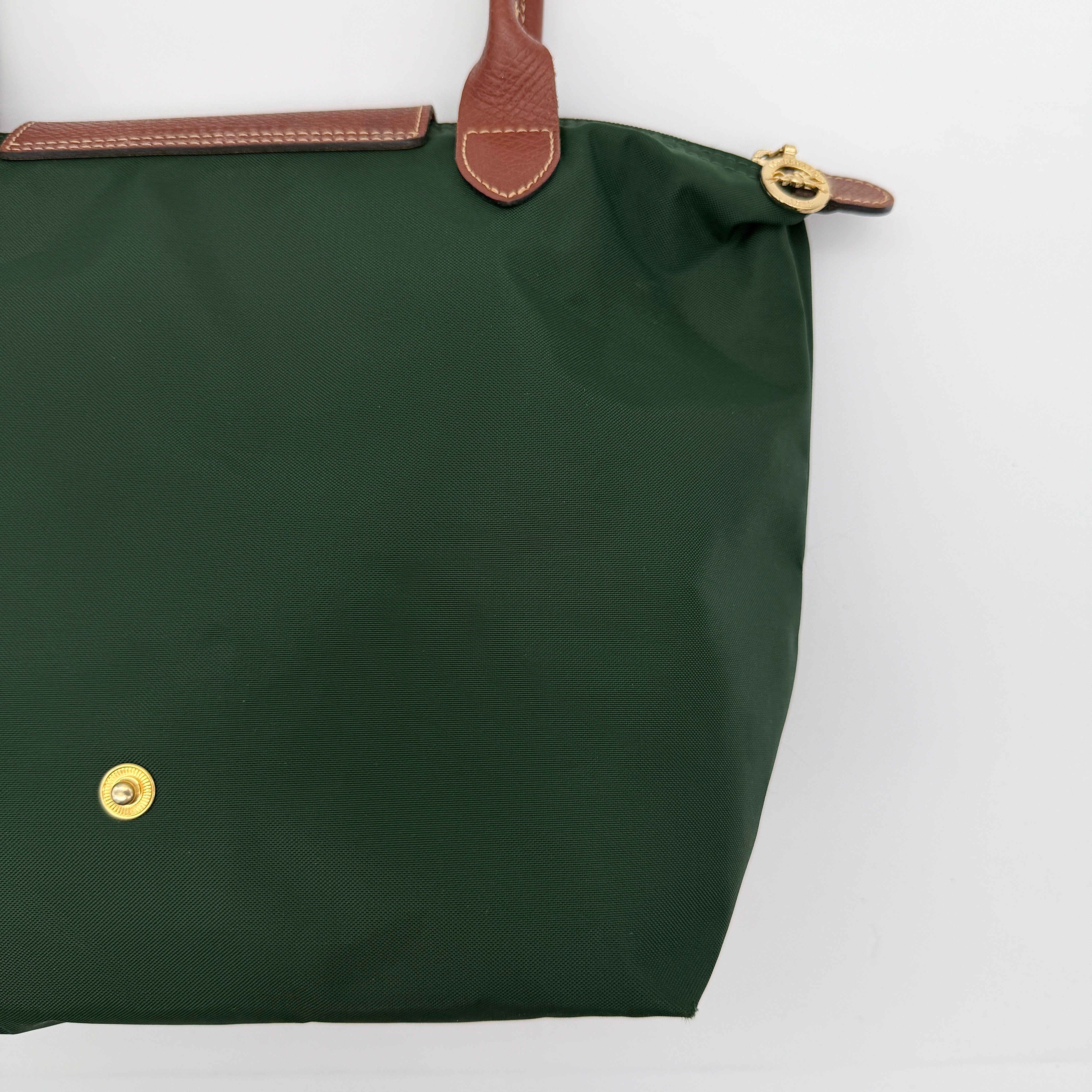 Longchamp Le Pliage Original Tote in green nylon with brown leather handles and gold hardware displayed against a white background.