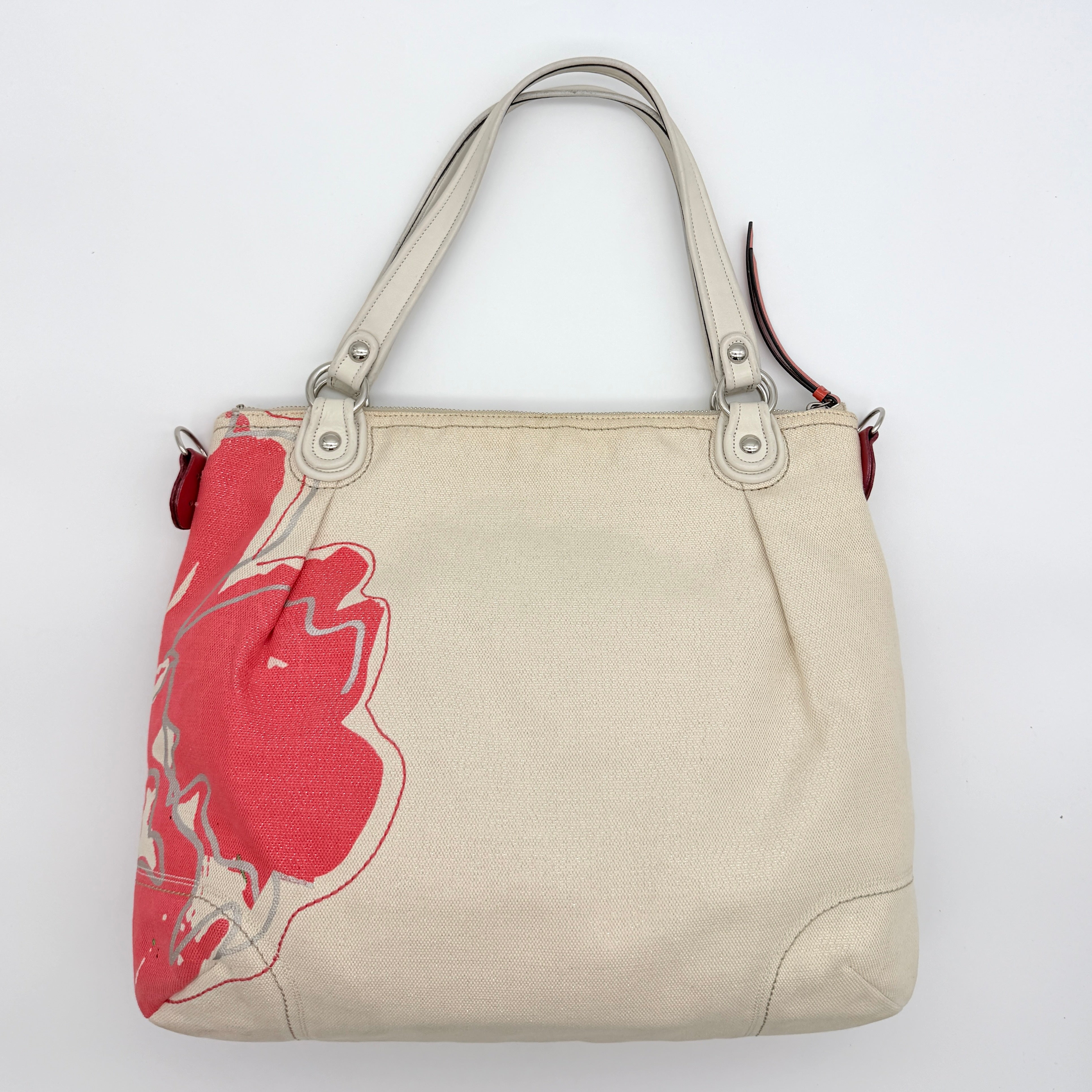 Coach Poppy Glam Floral Shoulder Bag in canvas with a bold multicolour floral print and cream leather handles, photographed on white.