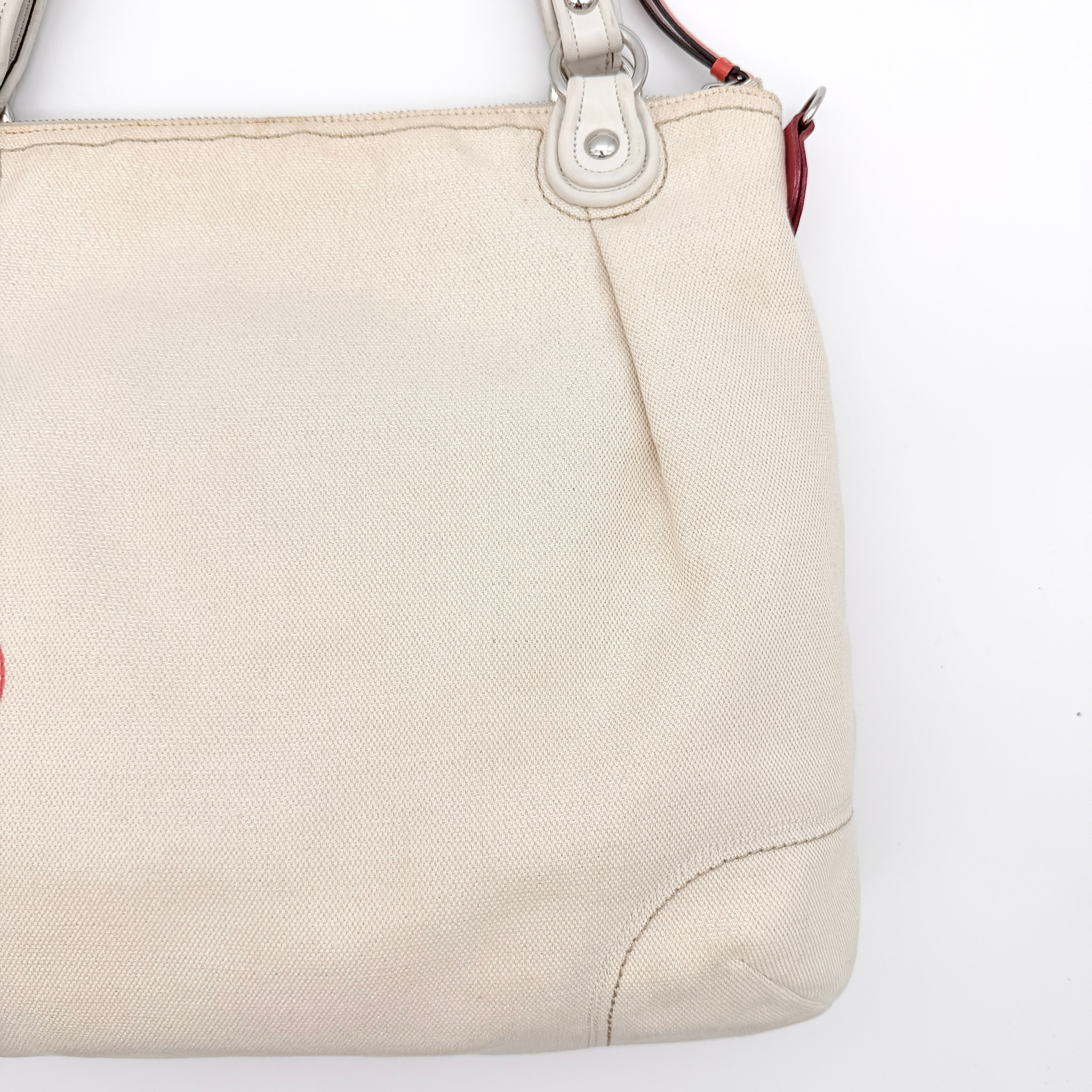 Coach Poppy Glam Floral Shoulder Bag in canvas with a bold multicolour floral print and cream leather handles, photographed on white.
