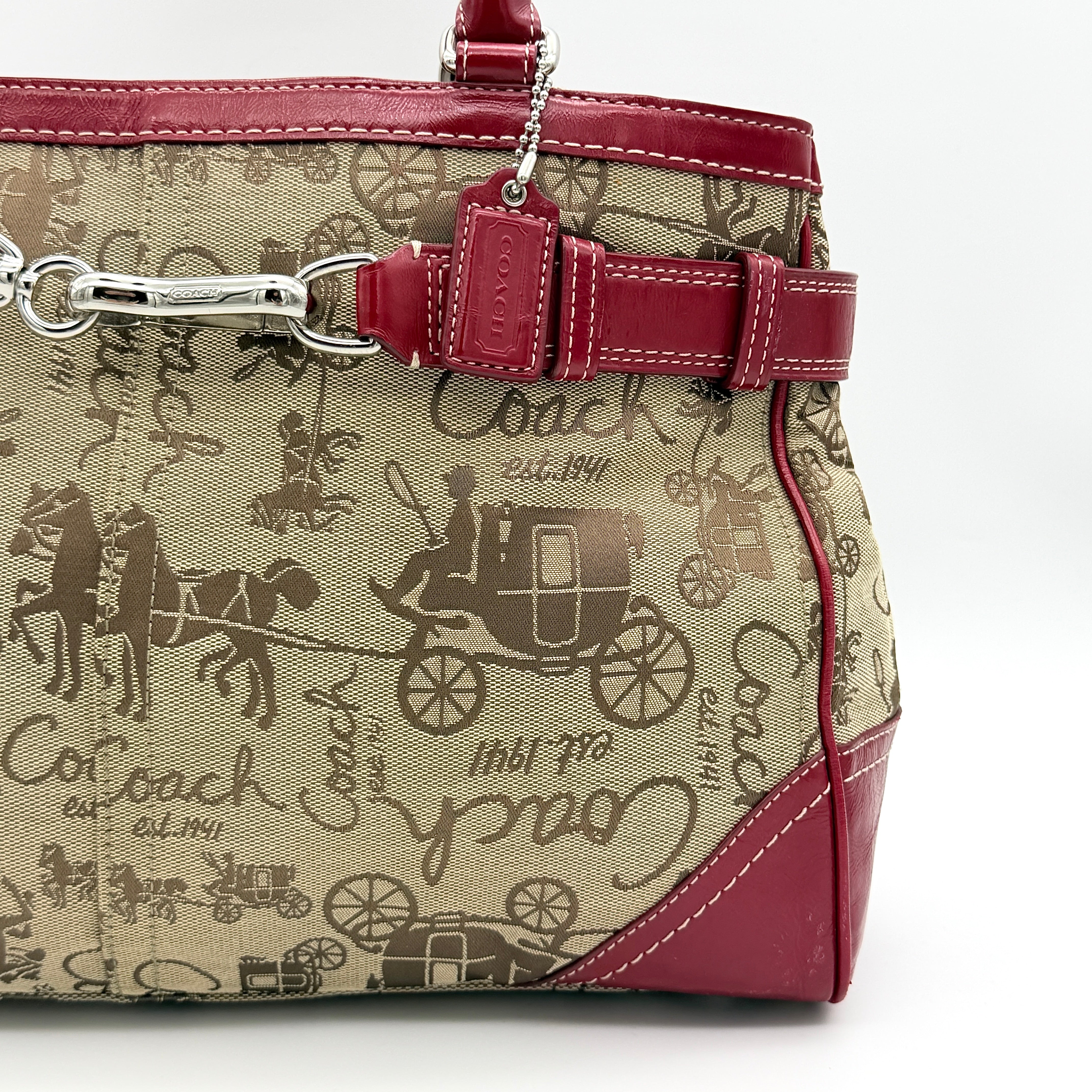 Coach Hampton Carryall in beige canvas with horse carriage motif, red leather trim, and double handles.