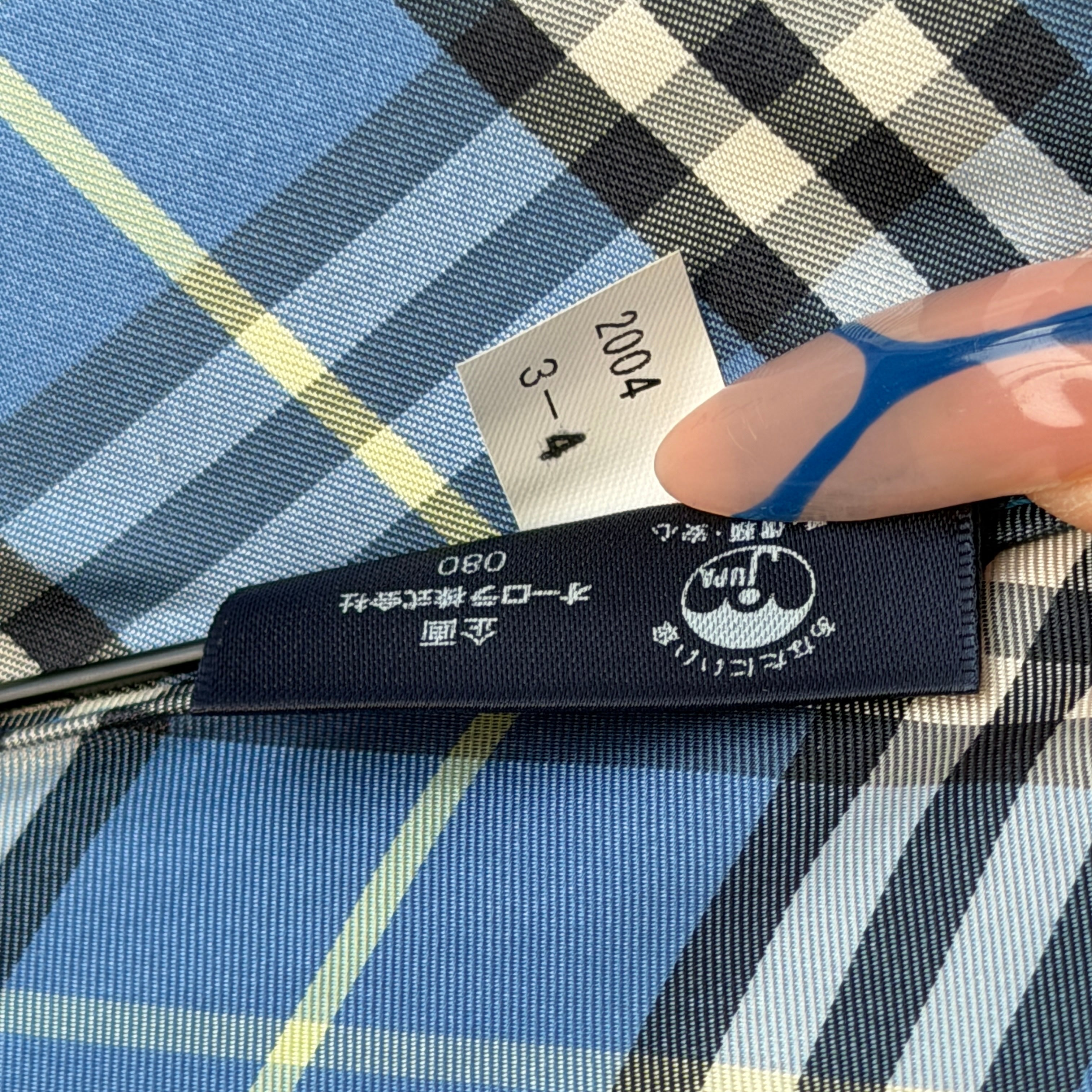 Burberry folding umbrella and matching pouch in blue Nova Check plaid, perfectly folded to showcase its classic pattern and refined finish.