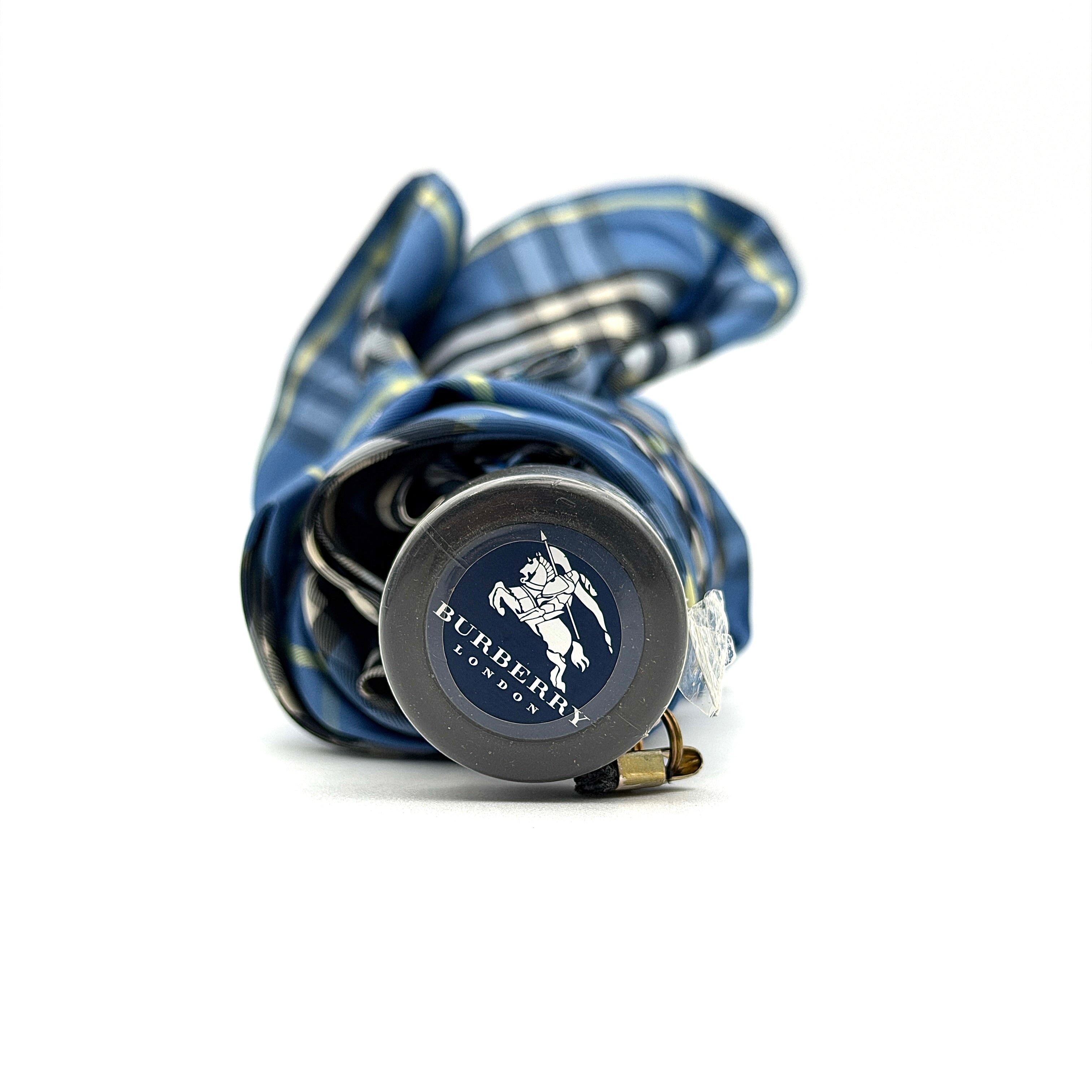 Burberry folding umbrella and matching pouch in blue Nova Check plaid, perfectly folded to showcase its classic pattern and refined finish.