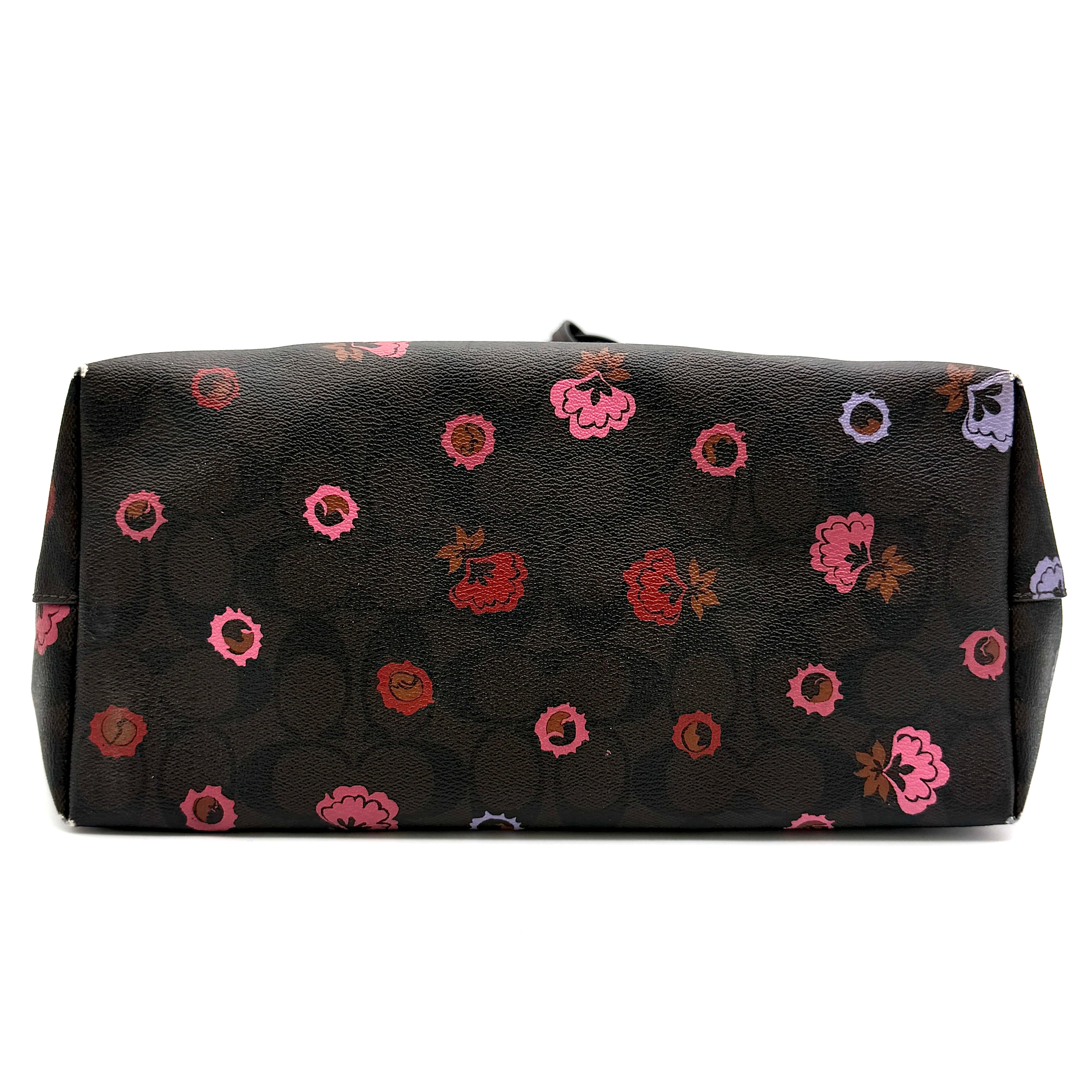 Coach brown coated canvas city tote with pink and lavender floral print, burgundy handles, and gold-tone logo at the front.