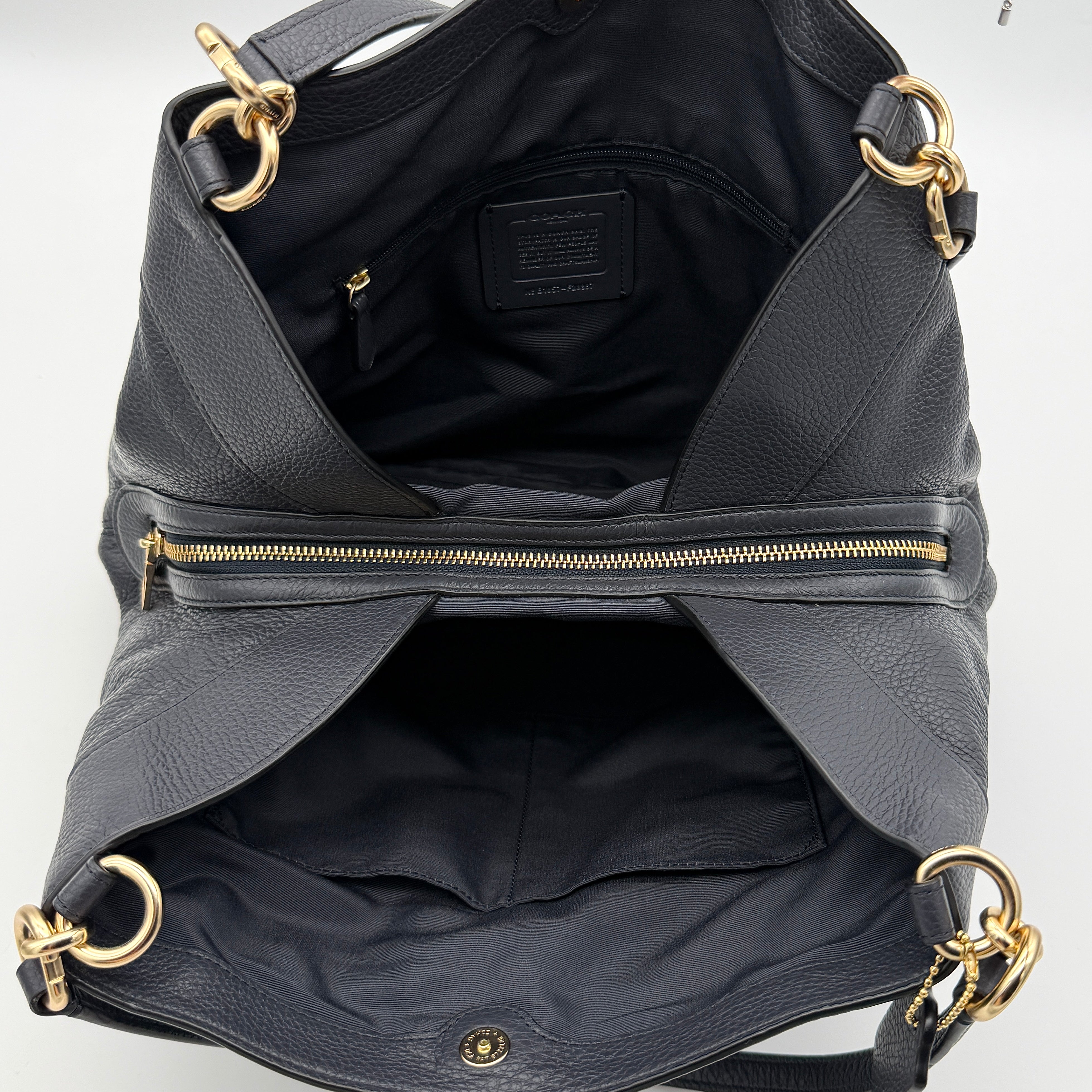 Coach Lexy shoulder bag in navy pebbled leather with gold-tone hardware and double handles.