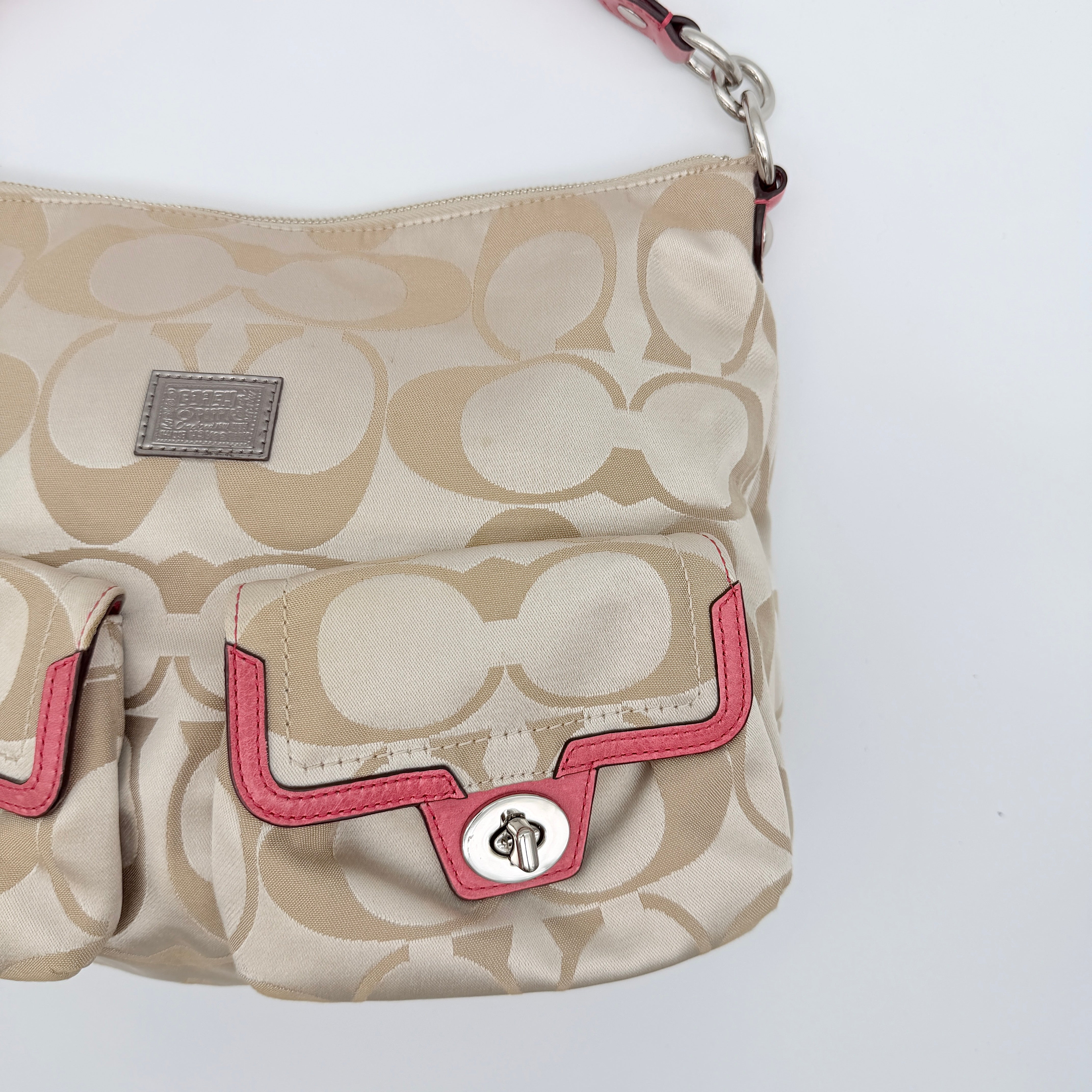 Coach Signature Poppy Pocket Hobo in beige sateen canvas with pink leather trim and silver hardware, front view with double pockets and charms.