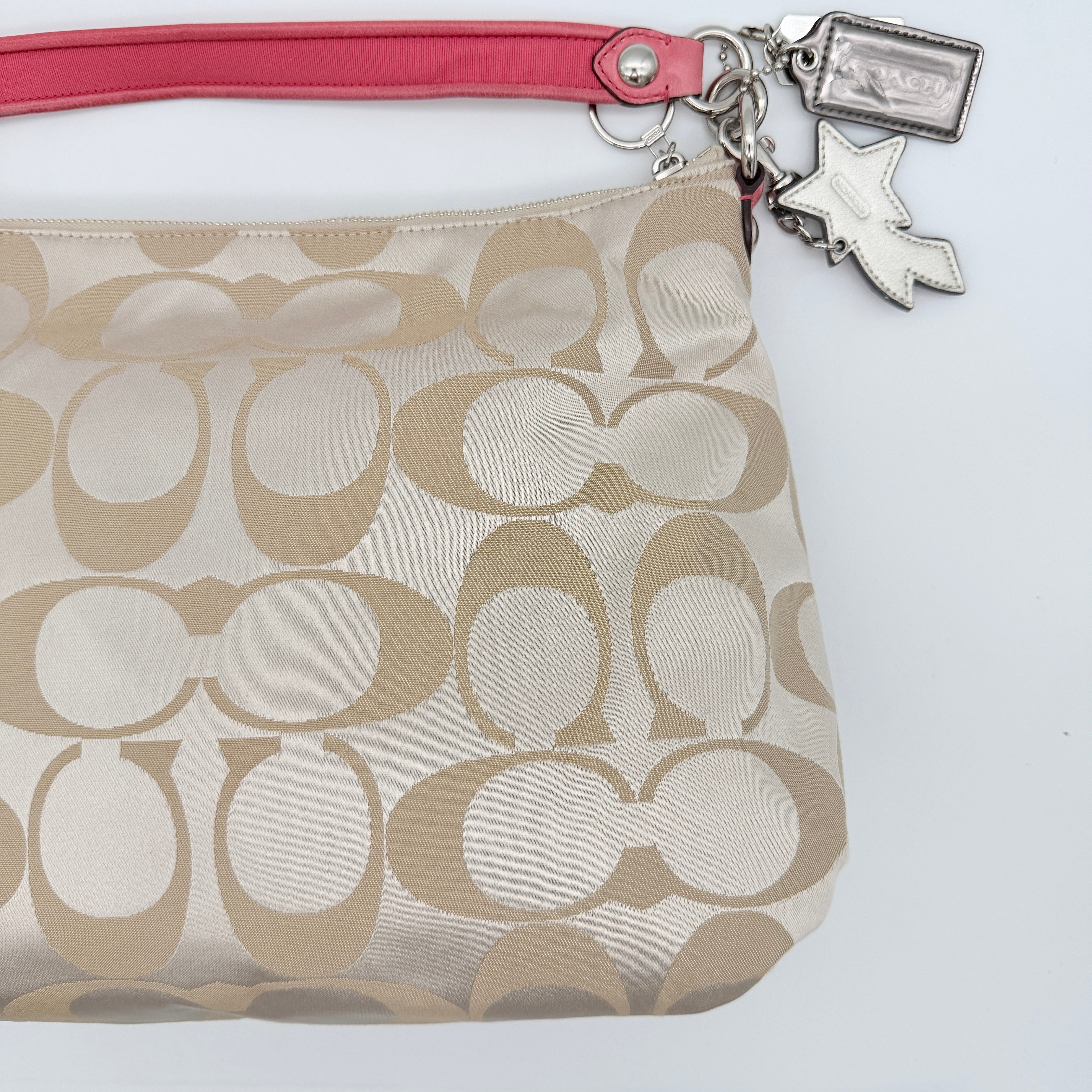 Coach Signature Poppy Pocket Hobo in beige sateen canvas with pink leather trim and silver hardware, front view with double pockets and charms.