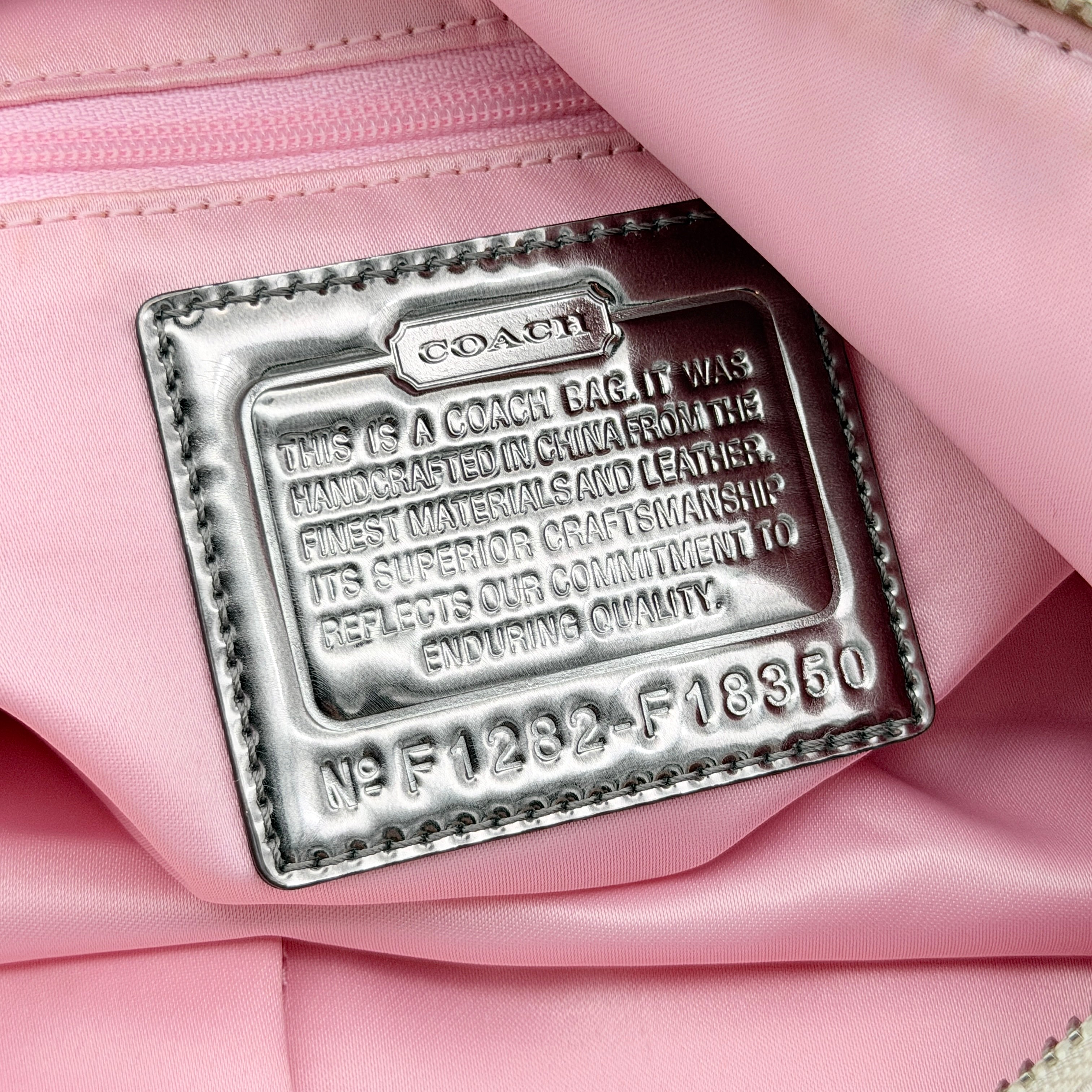Coach Signature Poppy Pocket Hobo in beige sateen canvas with pink leather trim and silver hardware, front view with double pockets and charms.