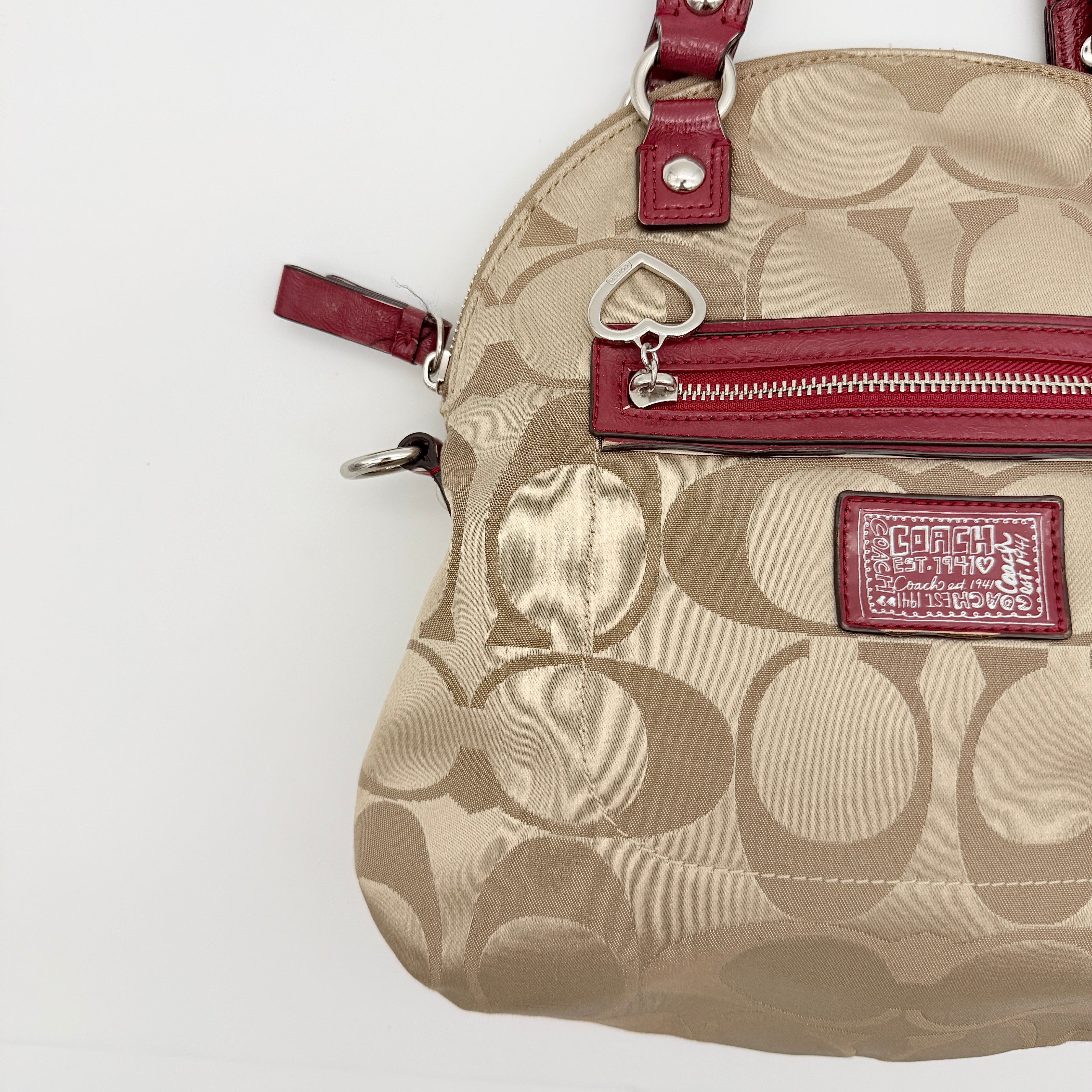 Coach Signature Poppy satchel in beige jacquard with red leather trim and detachable strap, shown with silver-tone hardware.