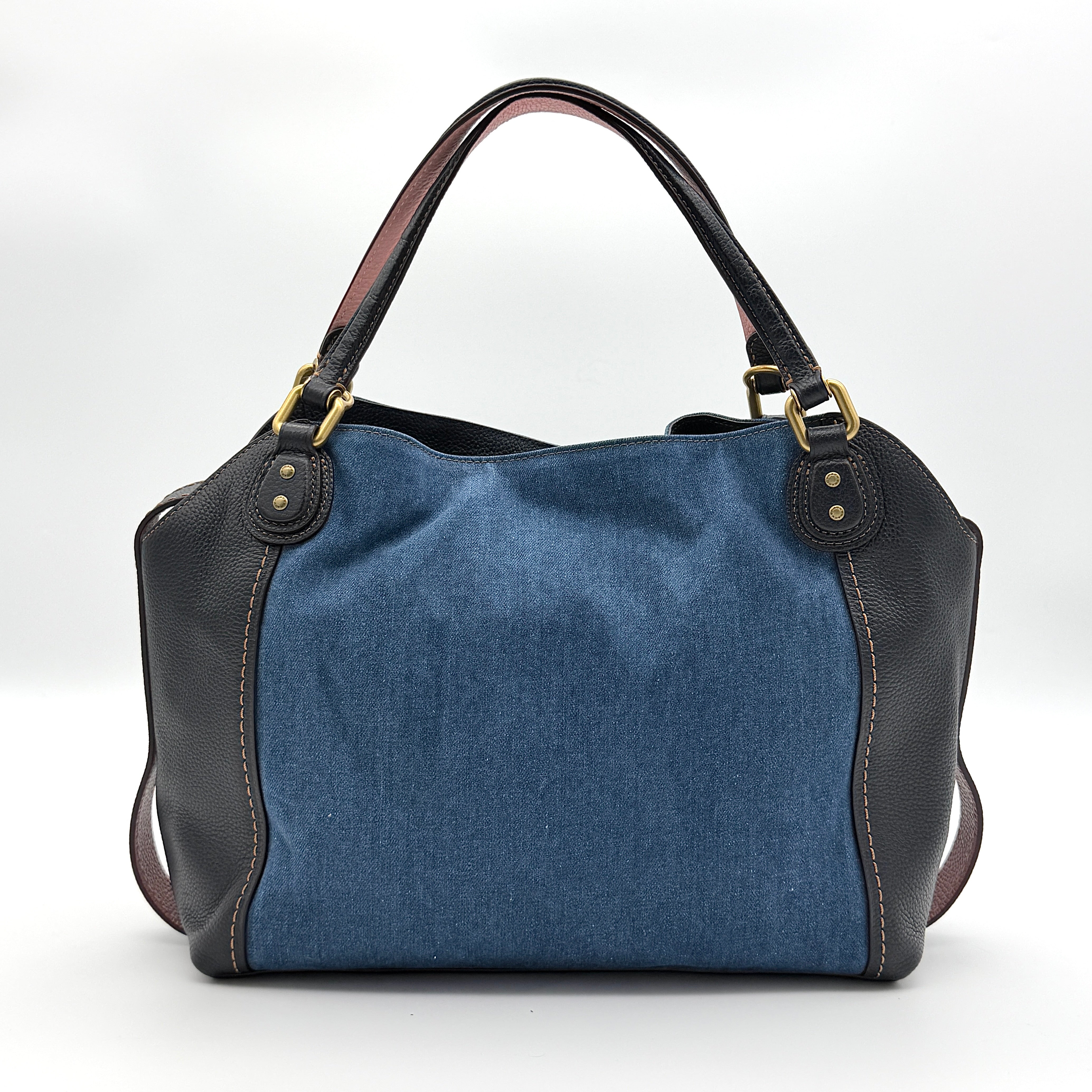 Coach Edie 2Way shoulder bag in navy denim with black leather trim, pink accents and gold hardware, shown with detachable strap.