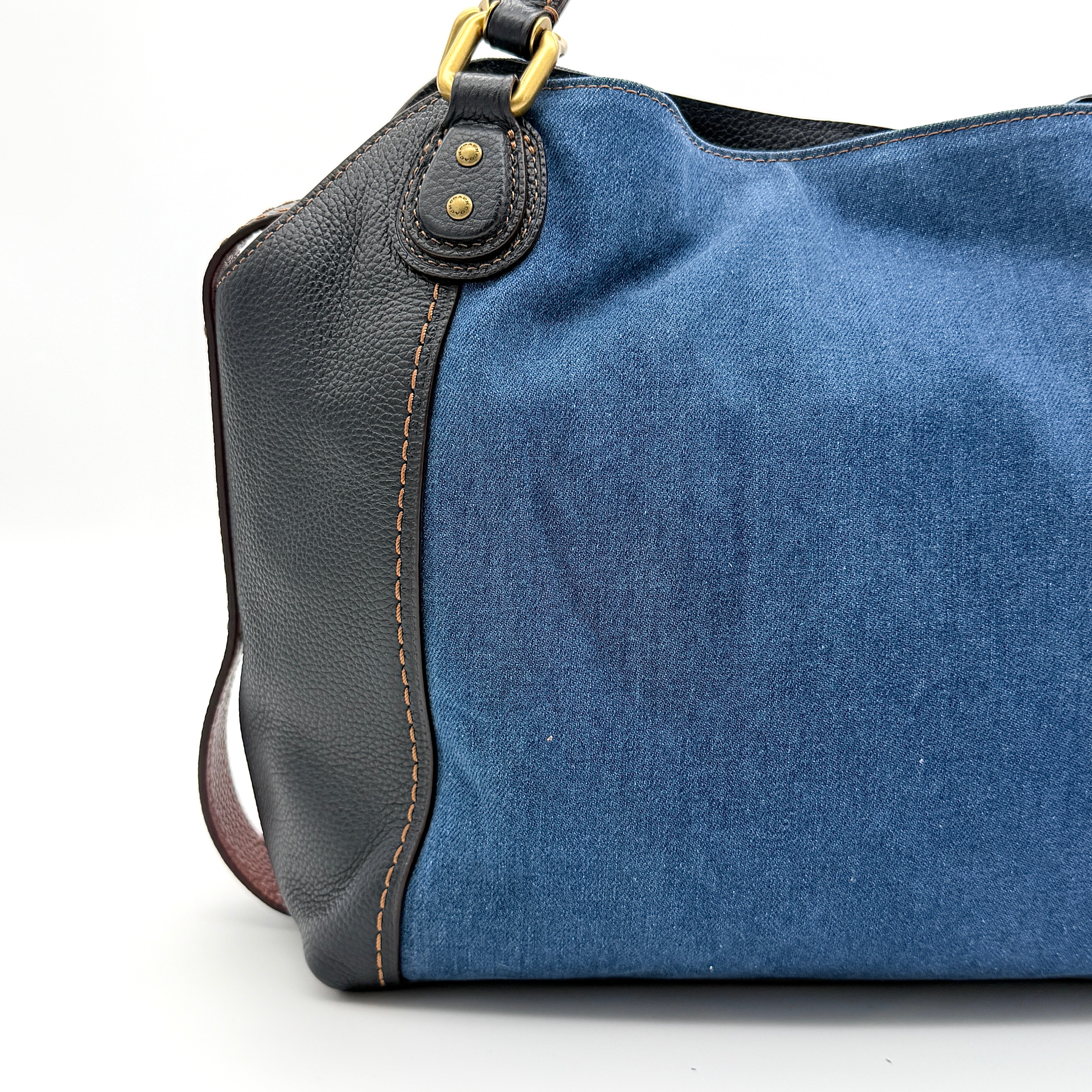 Coach Edie 2Way shoulder bag in navy denim with black leather trim, pink accents and gold hardware, shown with detachable strap.