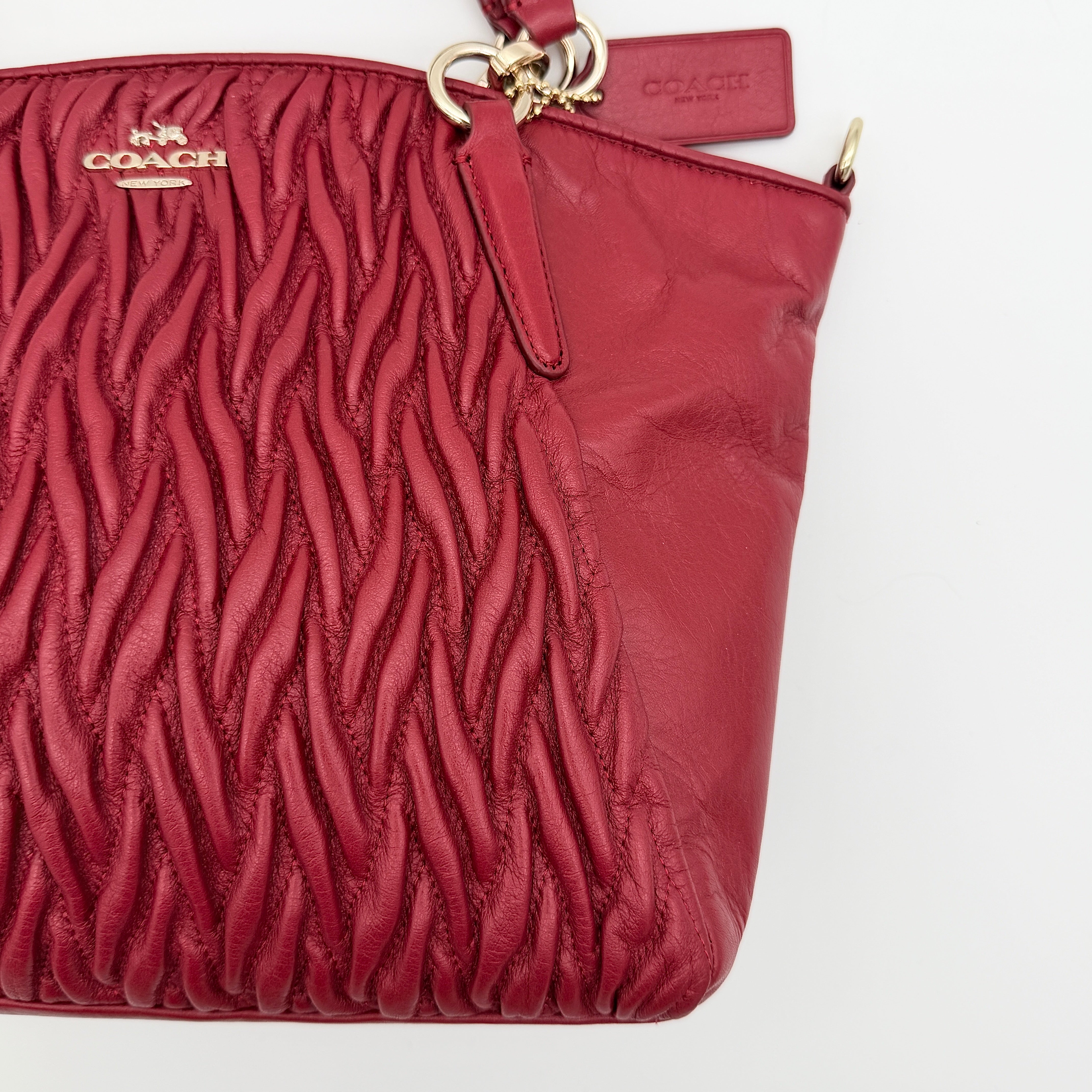 Coach Kelsey 2Way satchel in quilted red leather with gold-tone hardware and detachable strap, displayed against a white background.
