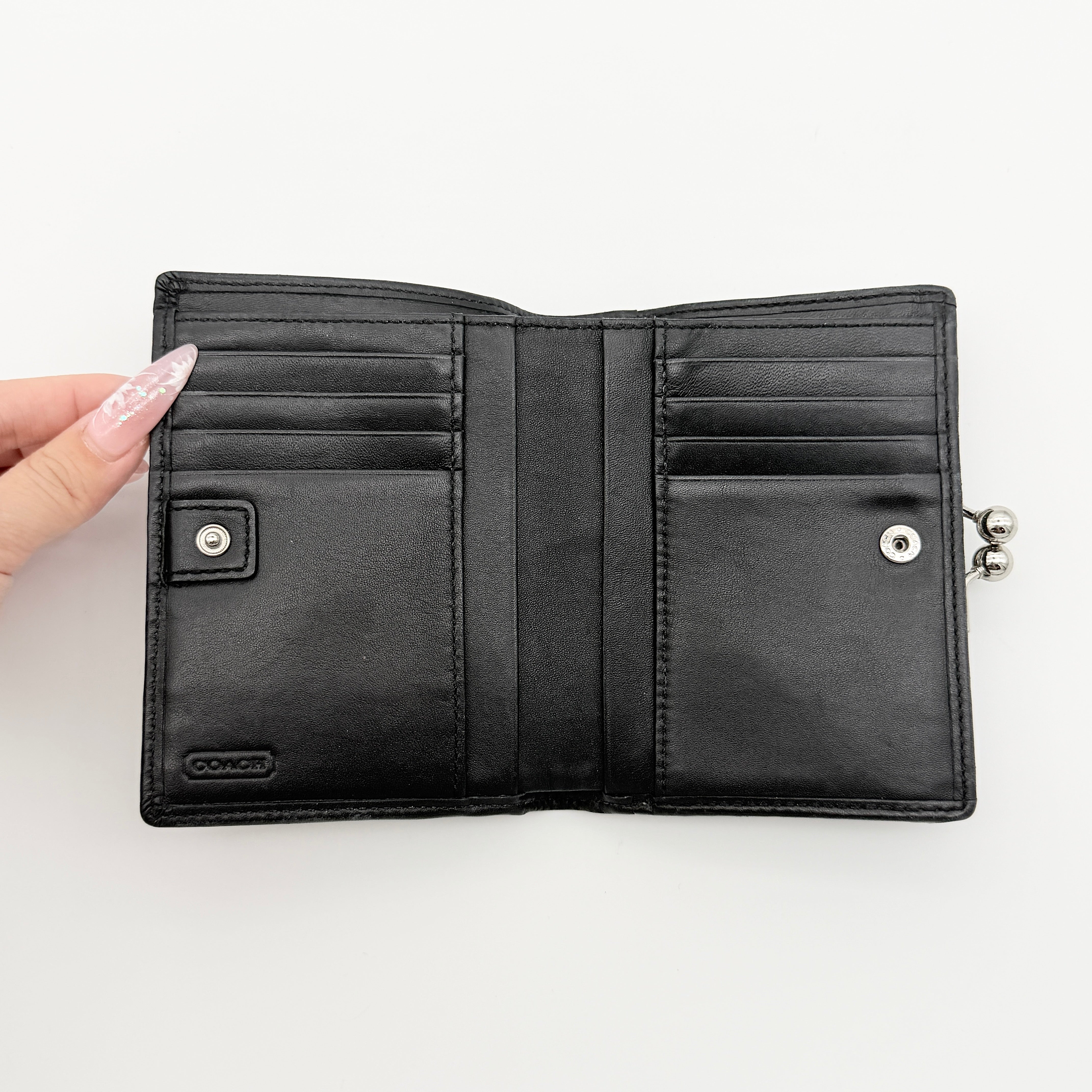 Coach Signature Stripe Kisslock Wallet in grey and black jacquard with black leather trim and silver-tone hardware, shown closed.
