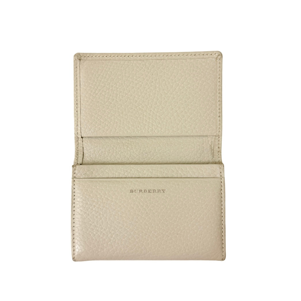 Burberry Nova Check card holder in ivory grained leather with subtle embossed logo, presented closed against a clean background.