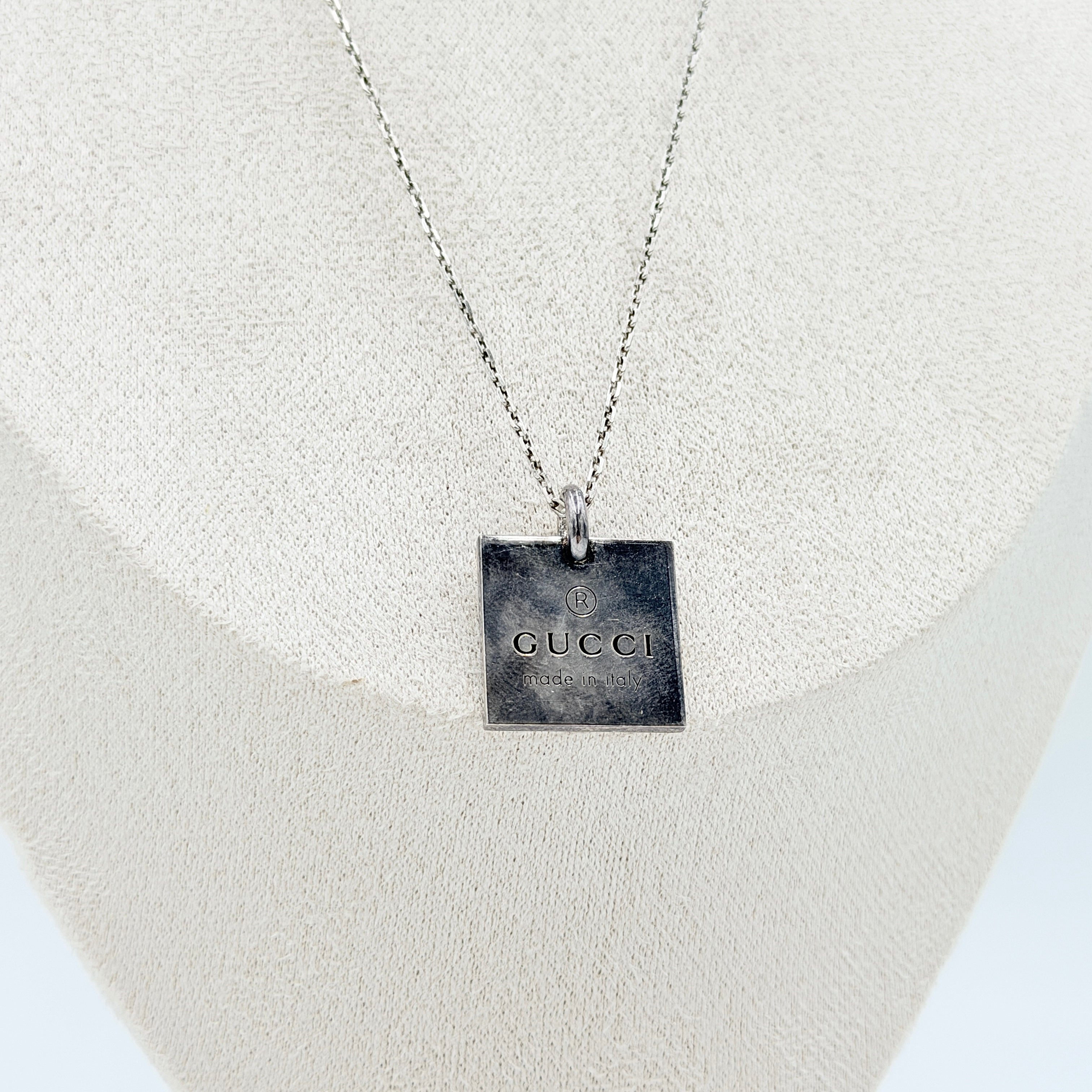 Gucci Trademark Square Plate Necklace in 925 silver with an engraved pendant and fine chain, artfully displayed against a clean background.