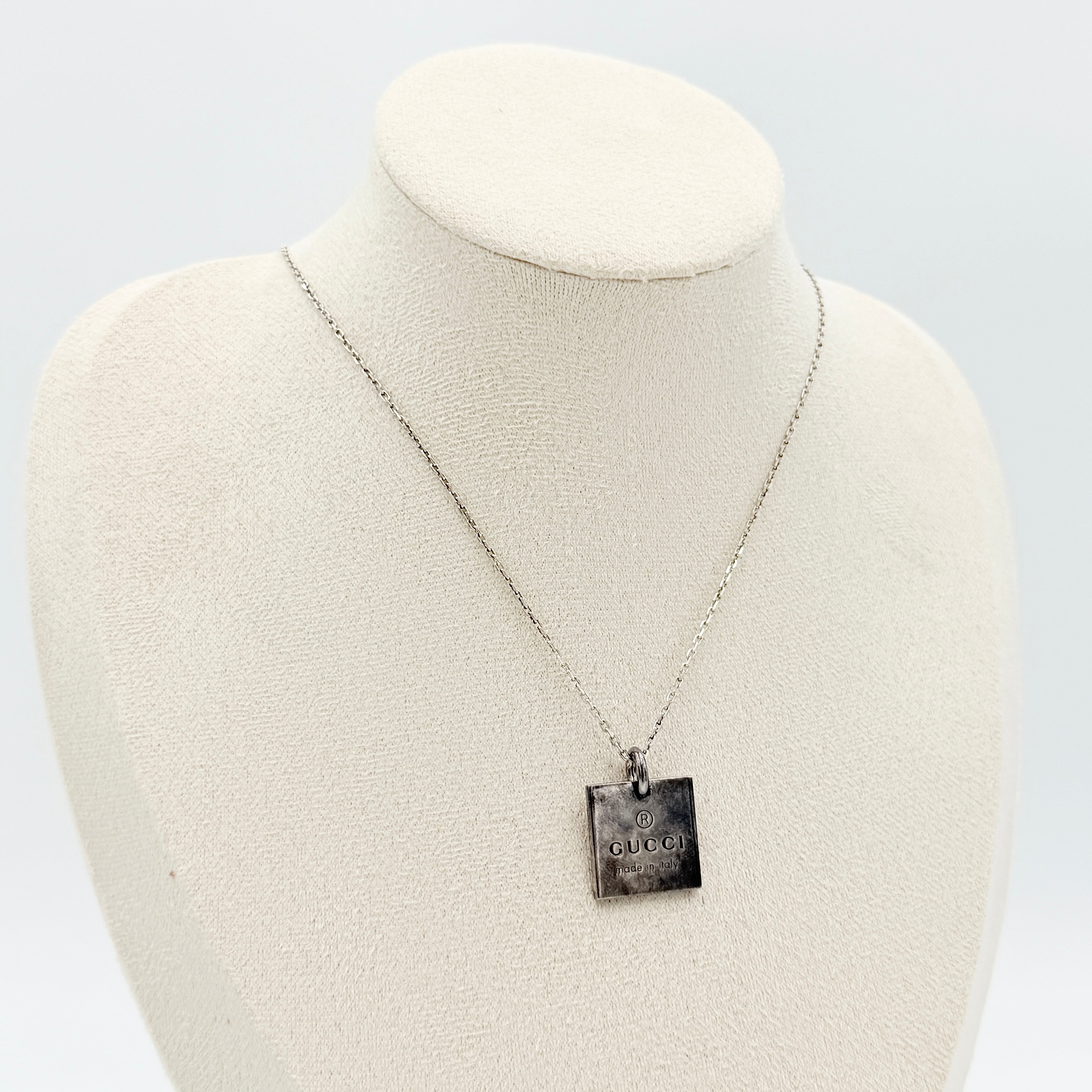 Gucci Trademark Square Plate Necklace in 925 silver with an engraved pendant and fine chain, artfully displayed against a clean background.