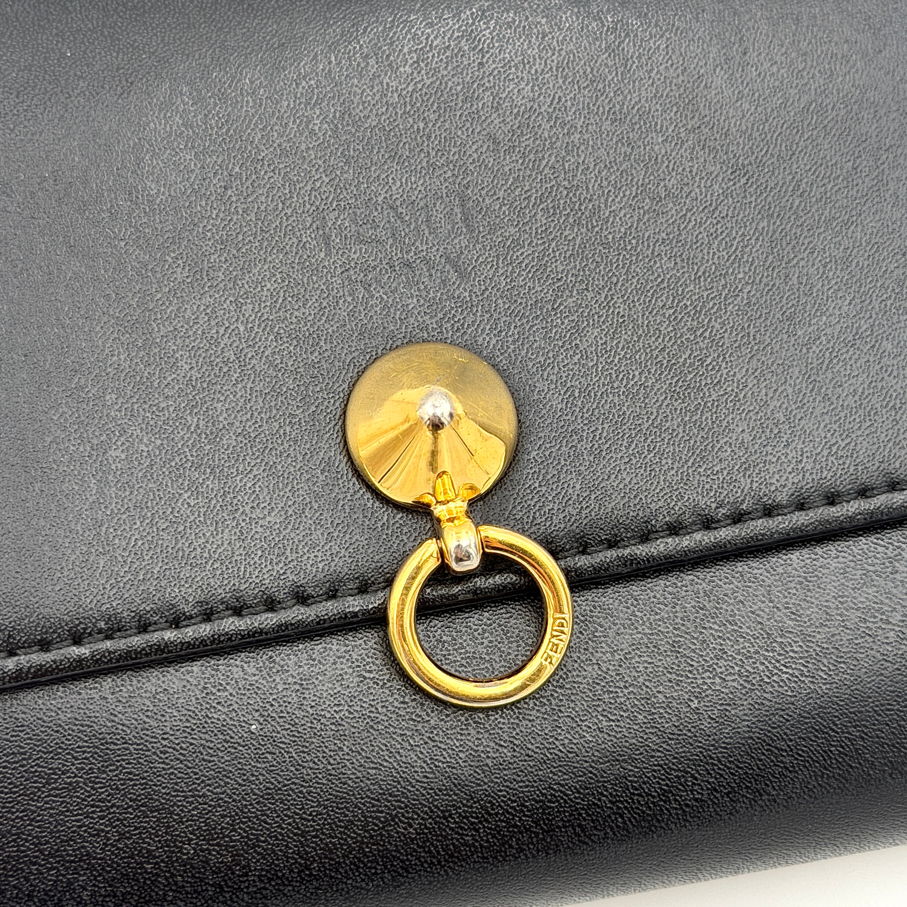 Fendi By The Way Leather Long Wallet in black with gold-tone disc and ring detail on the front flap.