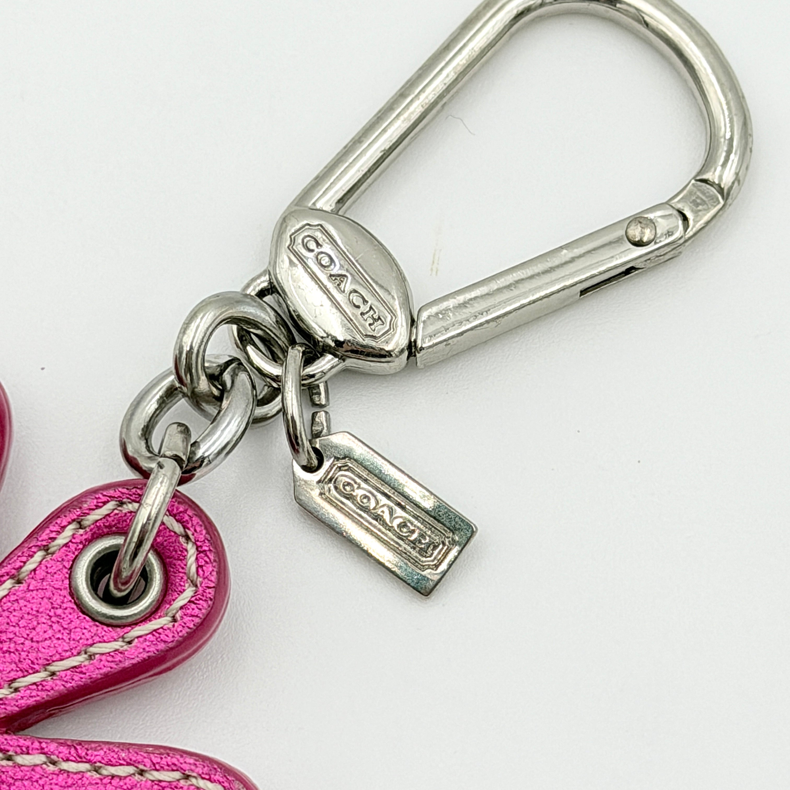 Coach Daisy Flow Bag Charm in magenta leather, featuring crystal accents and silver-tone hardware, styled with precise stitching.