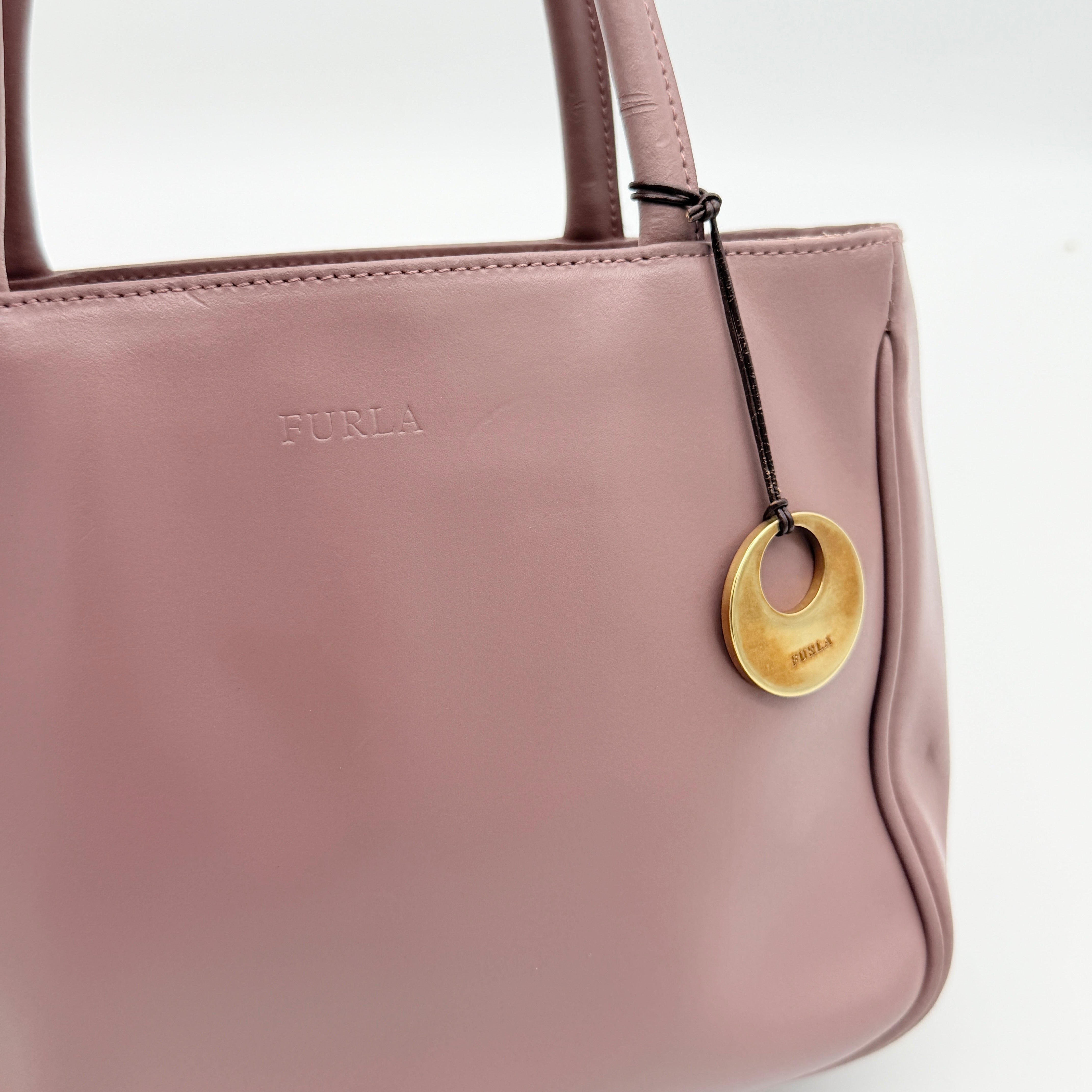 Furla 2Way Leather Handbag in pink with top handles, gold-tone charm, and a detachable strap, photographed on a white background.