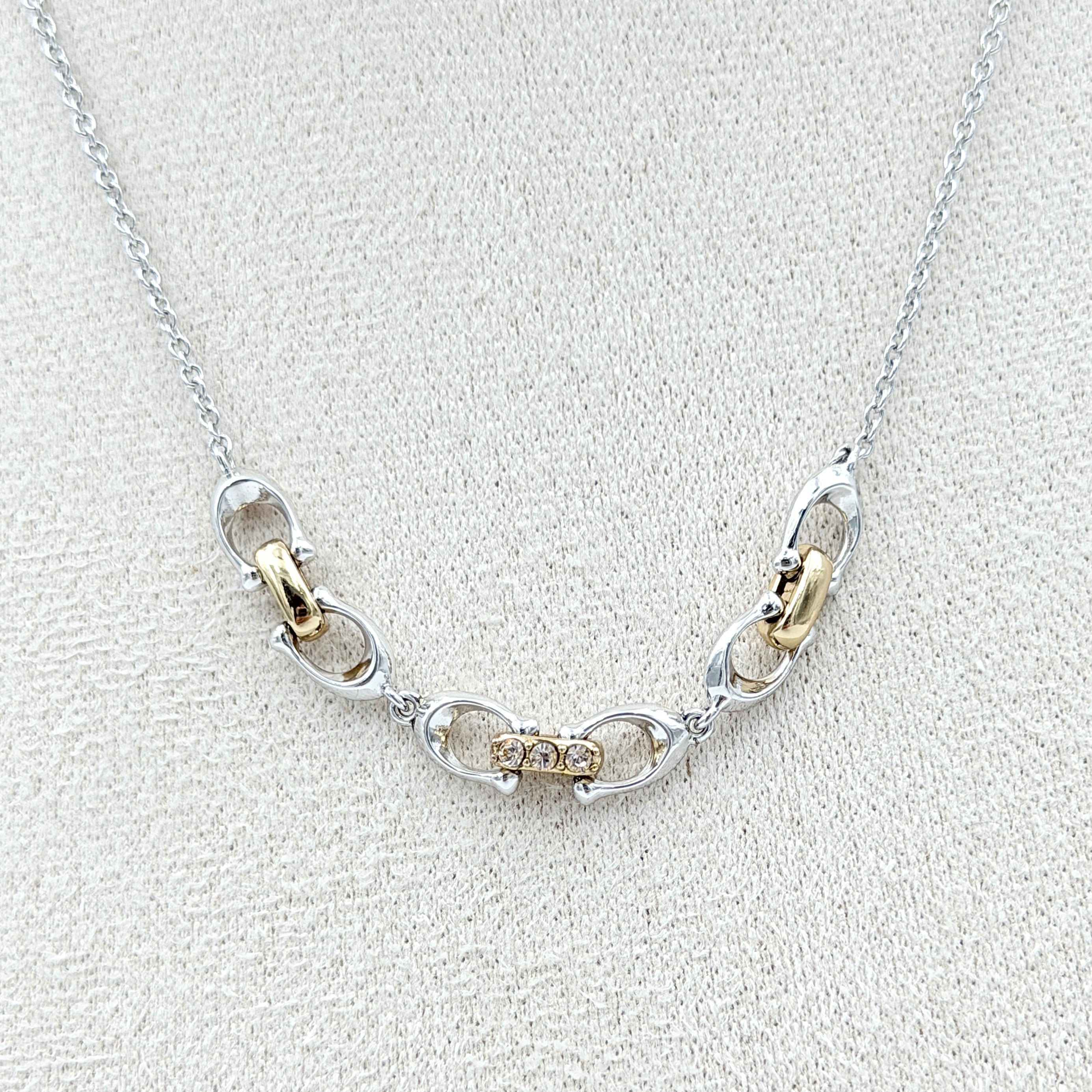 Coach Signature Linked Necklace in silver and gold tones featuring sculptural mixed-metal links and a central crystal accent.
