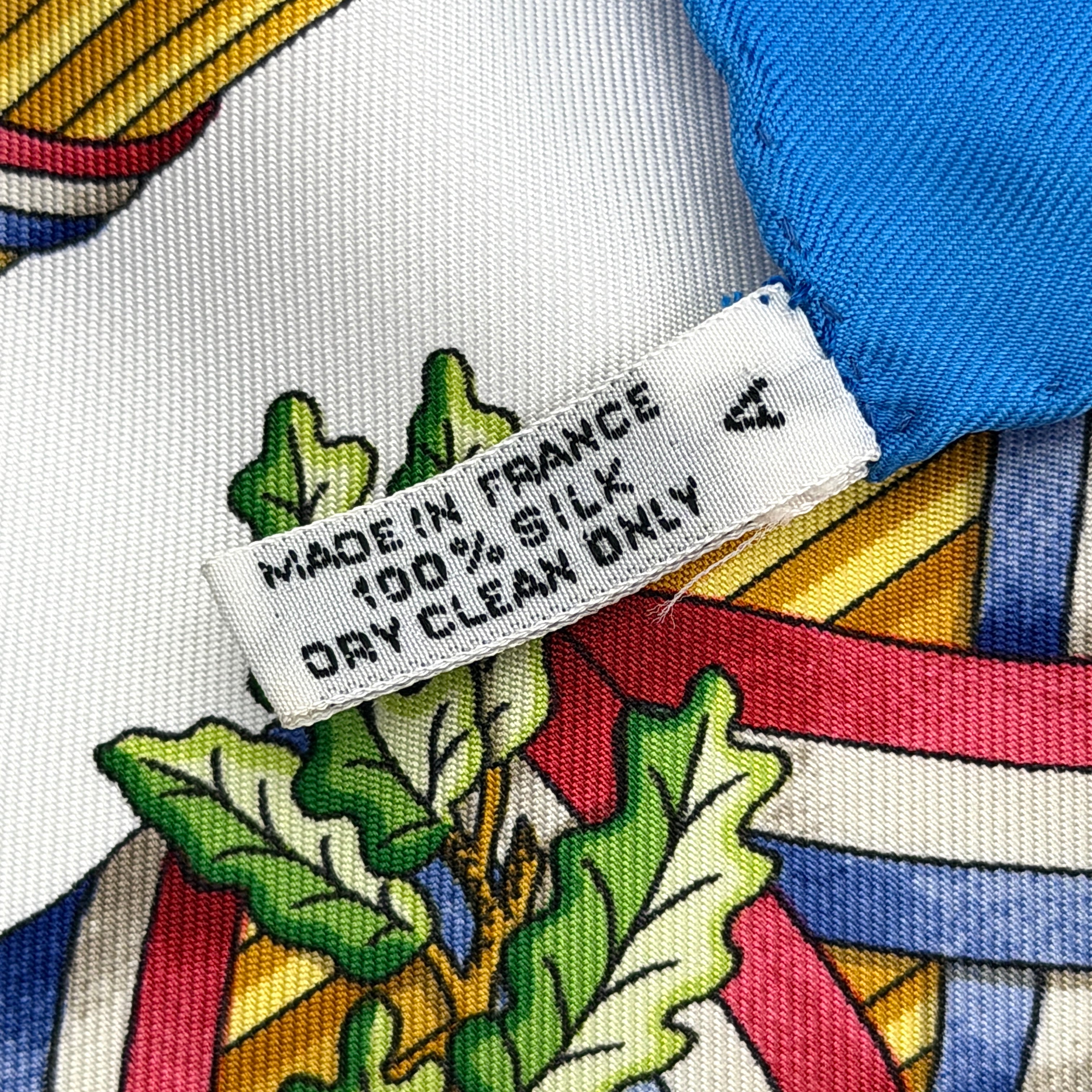 Hermès silk scarf with blue border, featuring a detailed French revolutionary motif and classical figures, shown with its signature orange box.