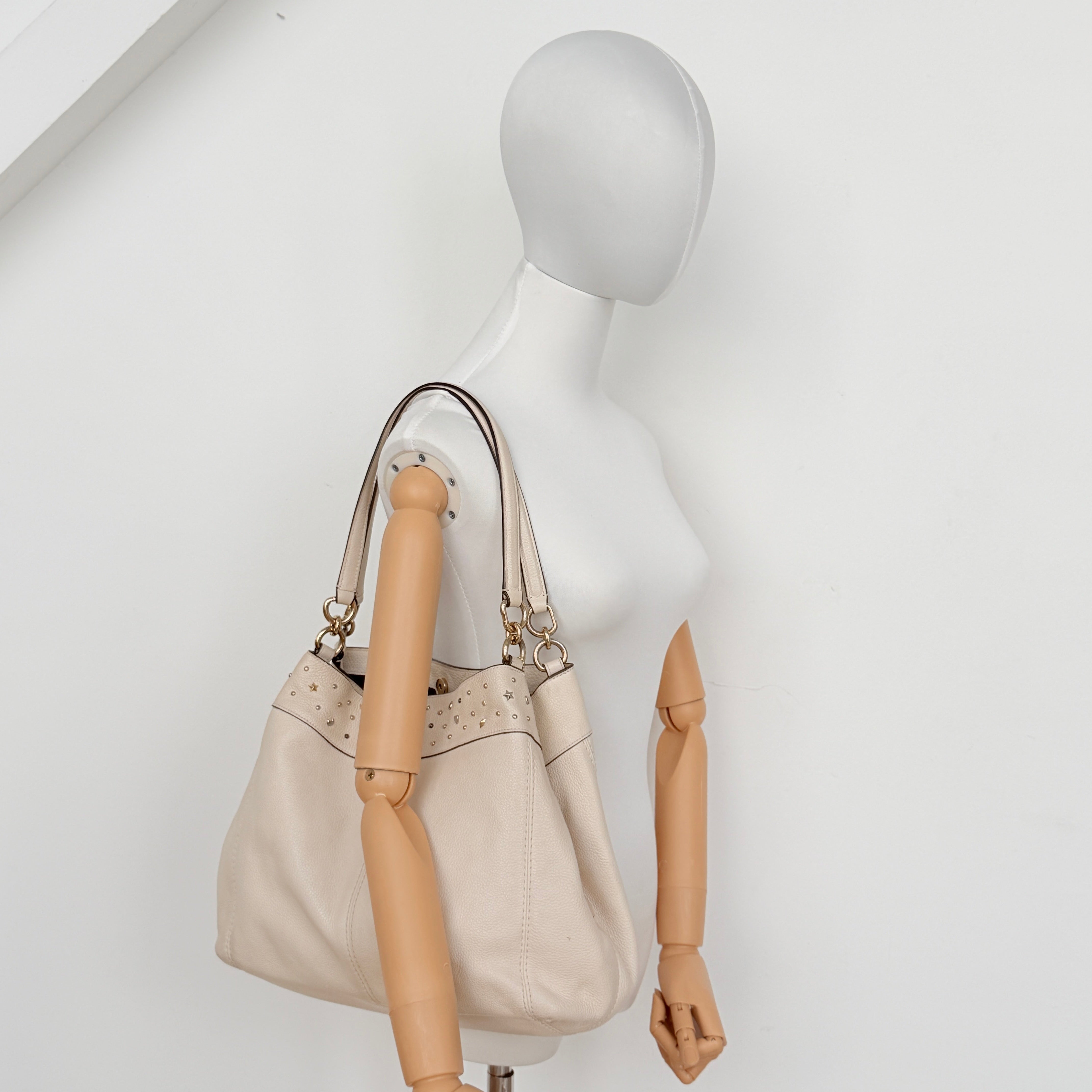 Coach Lexy Stardust Studded Chalk Hobo in ivory pebbled leather, adorned with mixed metal studs and dual handles.