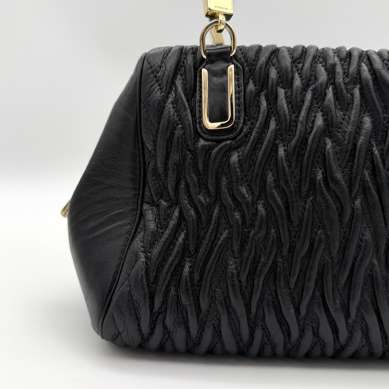 Coach Madison Gathered Twist satchel in black leather with gold hardware and detachable strap, styled on a white background.