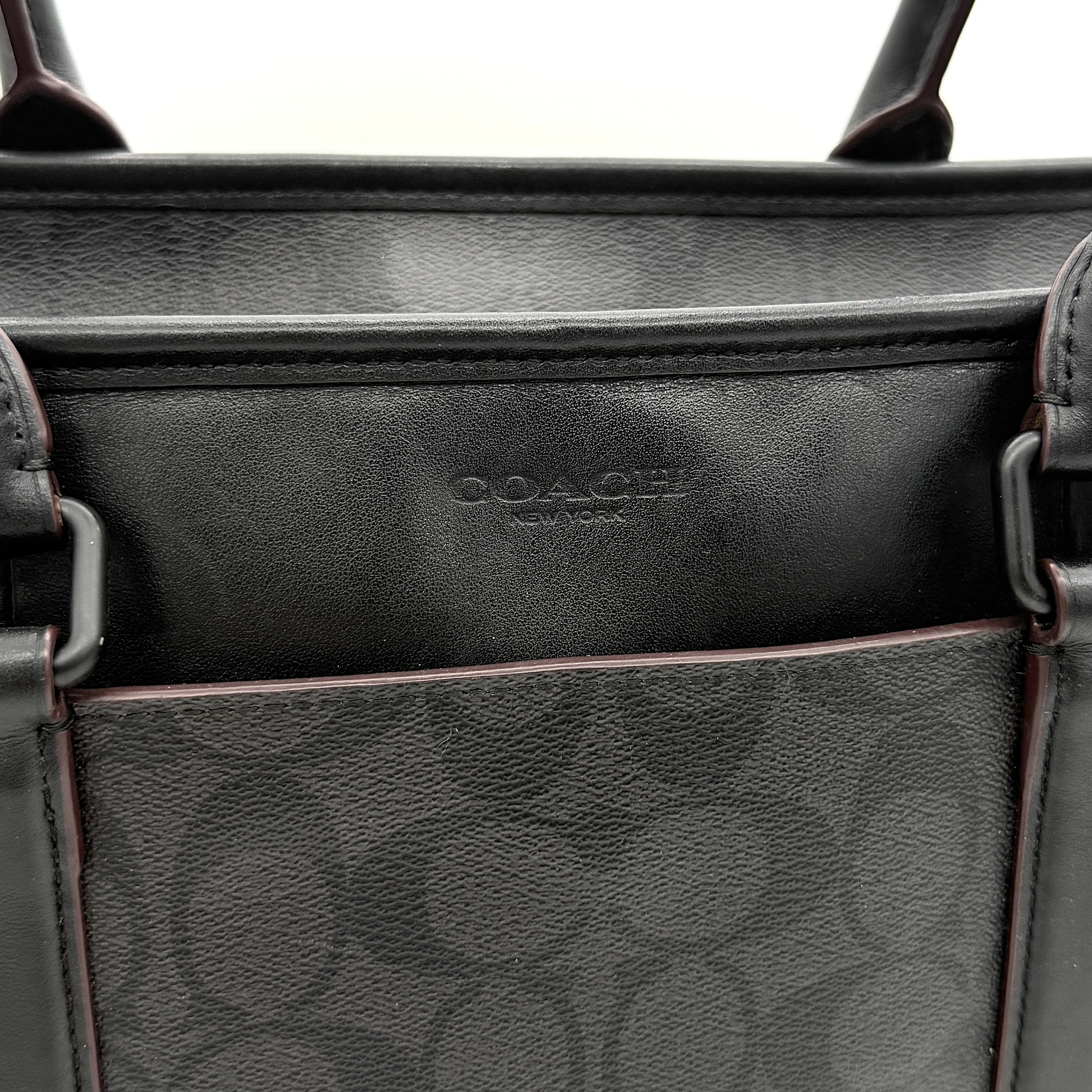 Coach Perry Business Tote in charcoal black signature canvas with double handles and detachable strap, shown upright against a white background.