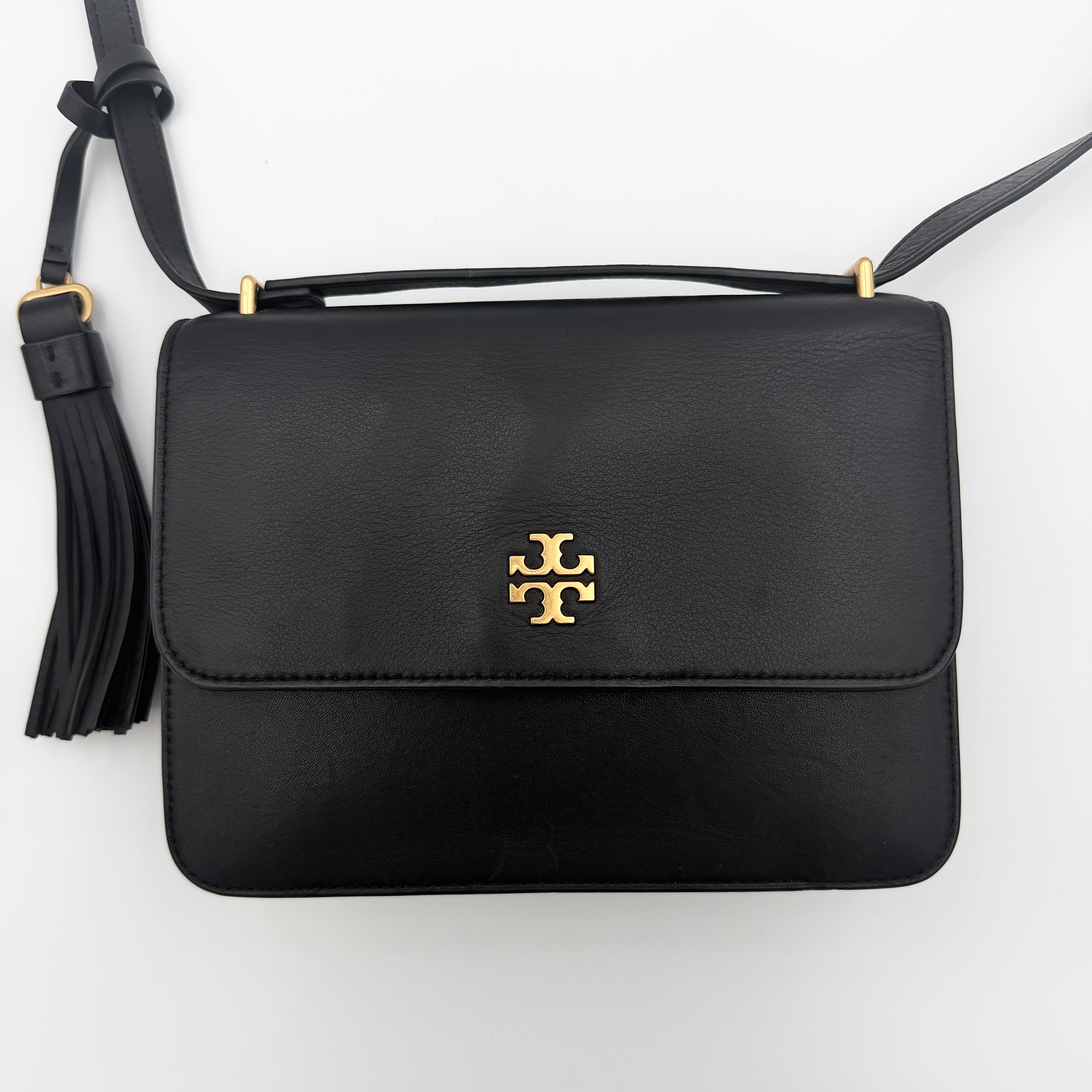 Tory Burch Brooke Crossbody Bag in black leather with gold-tone logo and a braided chain strap, elegantly displayed against a white backdrop.