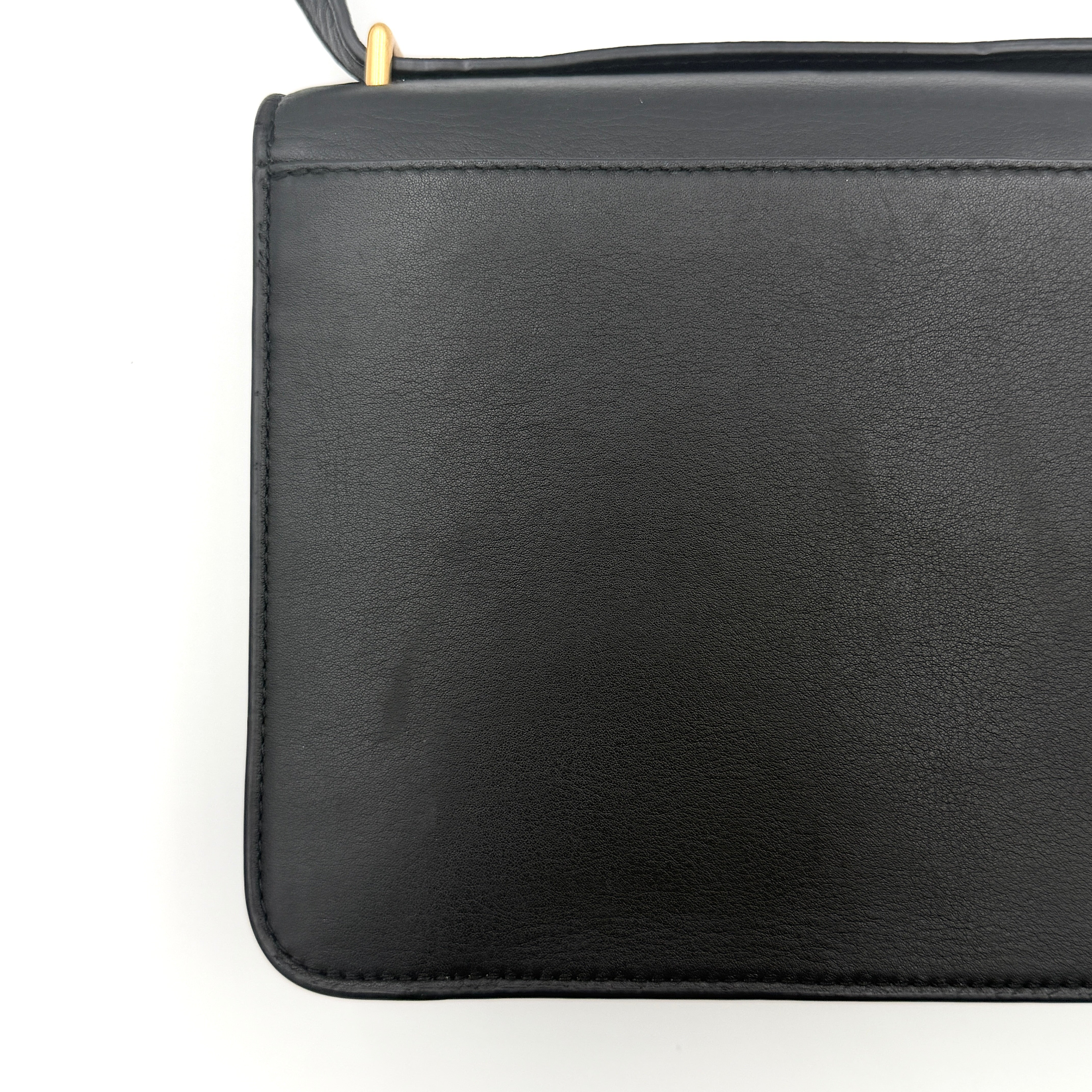 Tory Burch Brooke Crossbody Bag in black leather with gold-tone logo and a braided chain strap, elegantly displayed against a white backdrop.