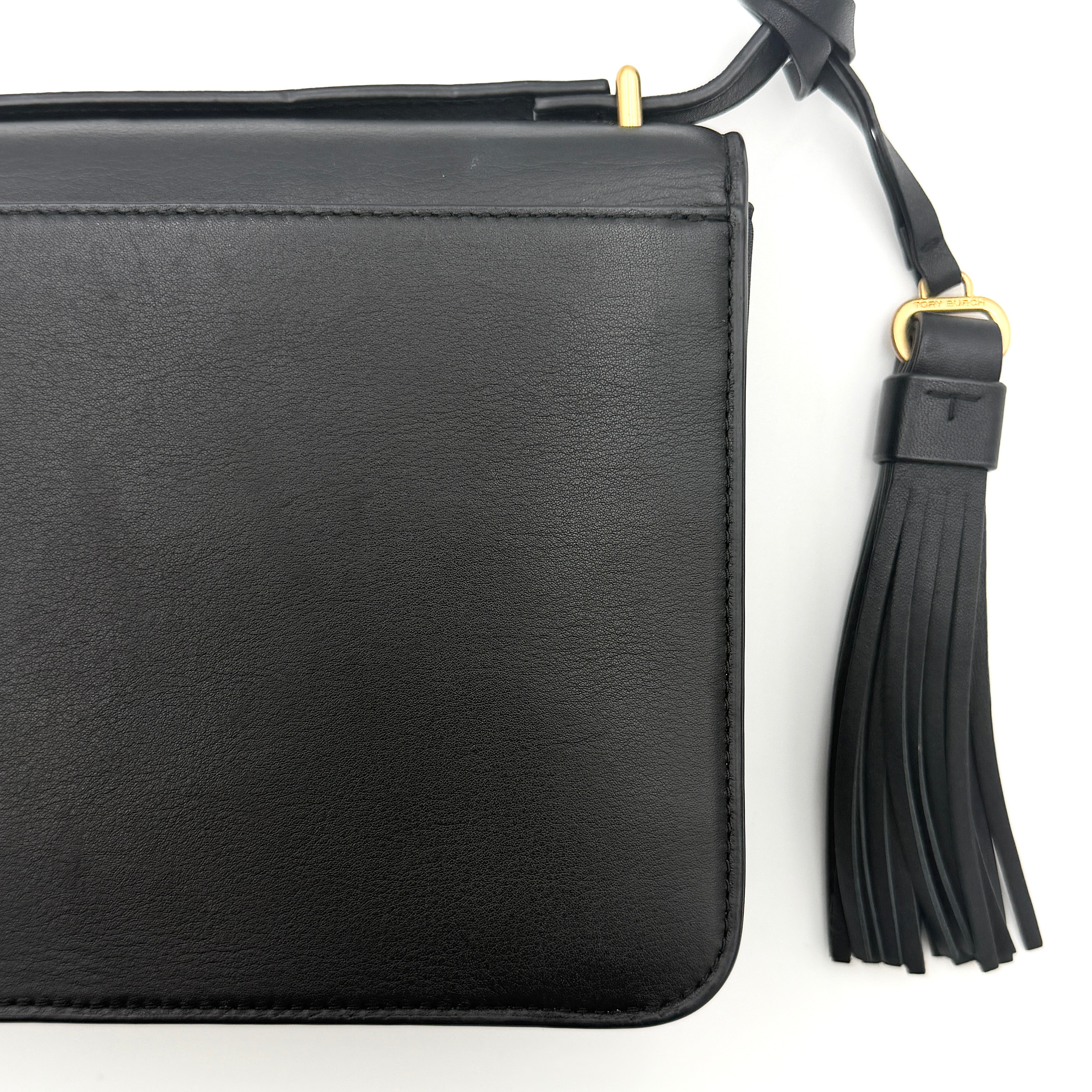 Tory Burch Brooke Crossbody Bag in black leather with gold-tone logo and a braided chain strap, elegantly displayed against a white backdrop.