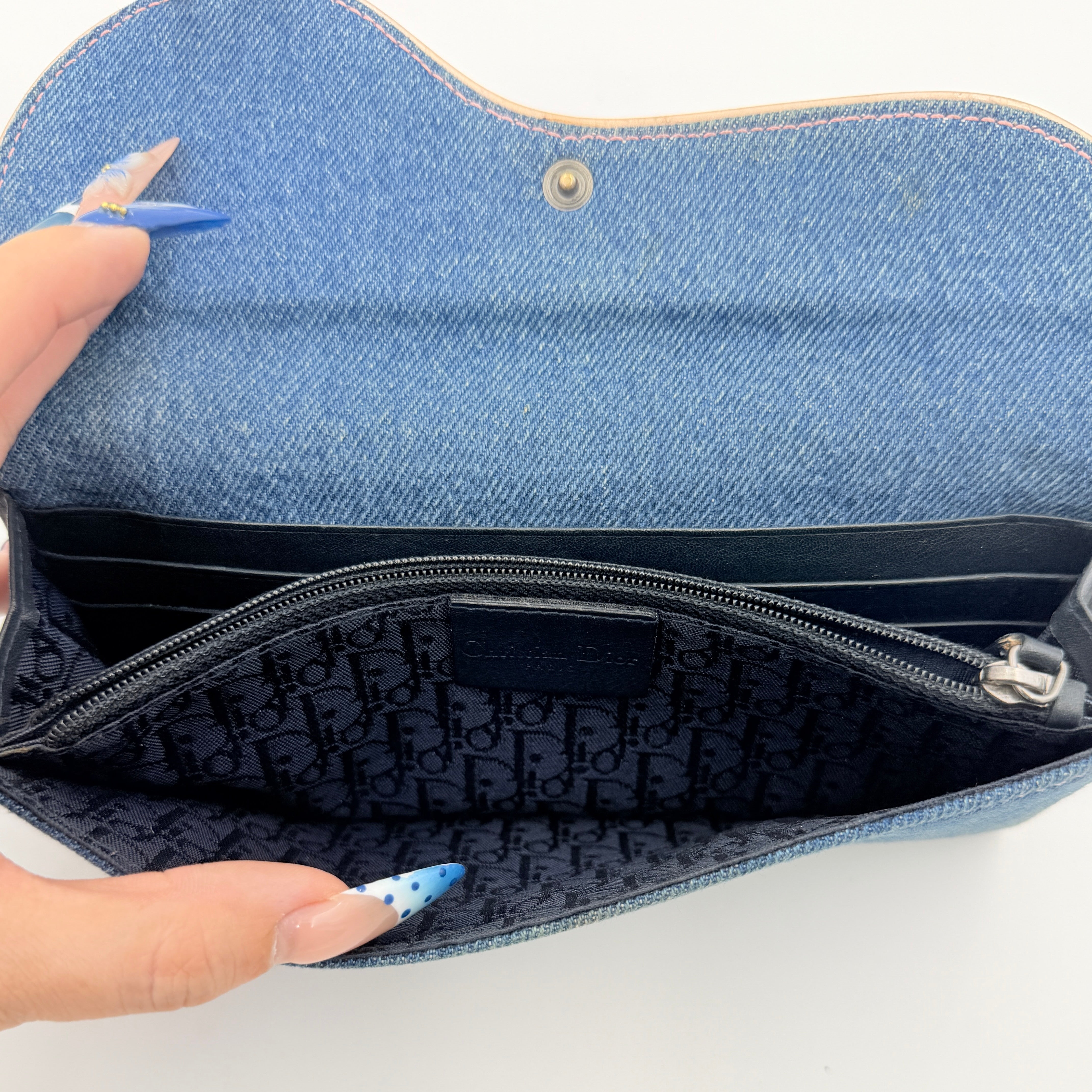 Dior Saddle Denim Wallet in blue denim with signature curved silhouette and silver-tone 'D' charm on the front flap.